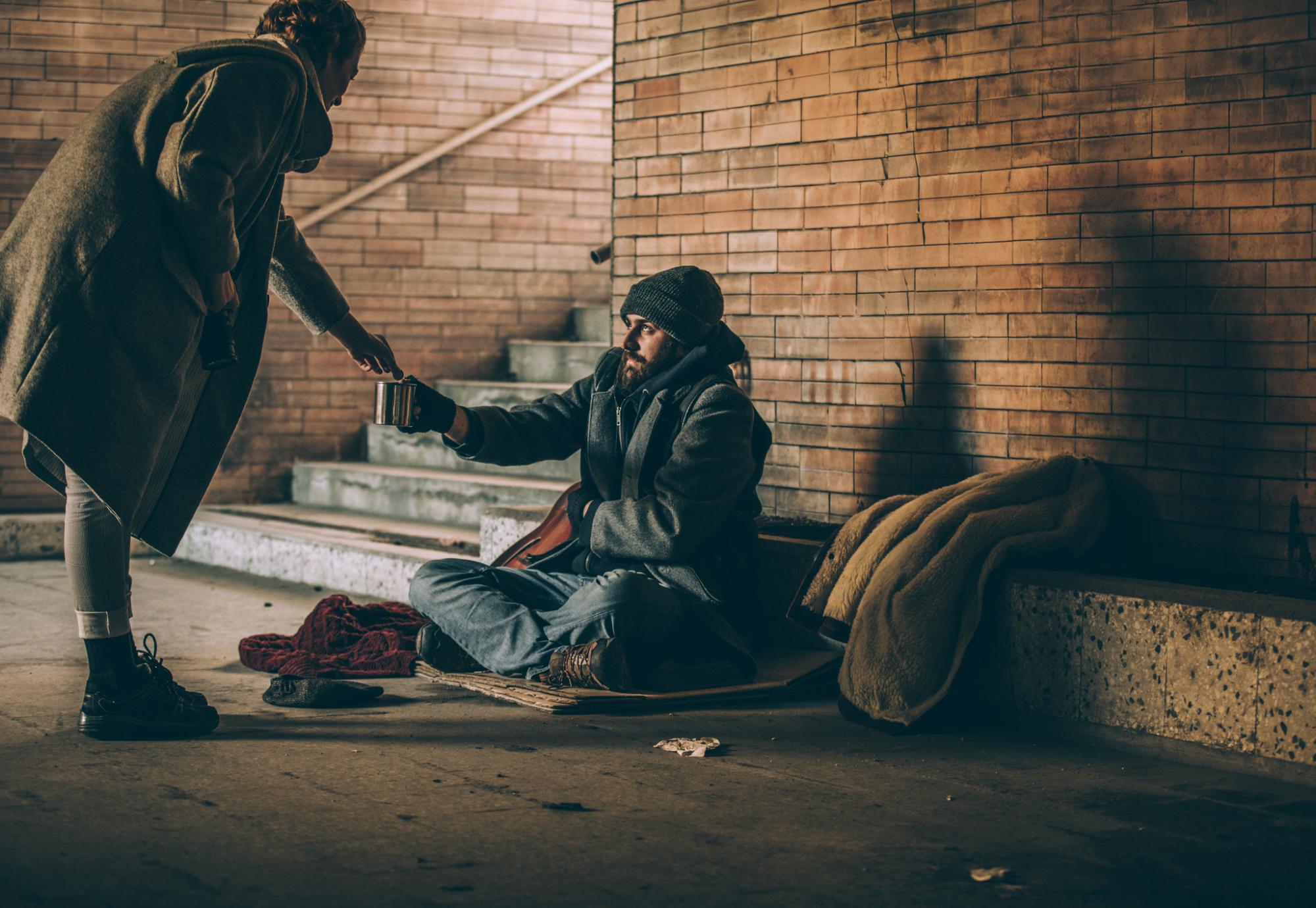 Homeless man and woman giving him money