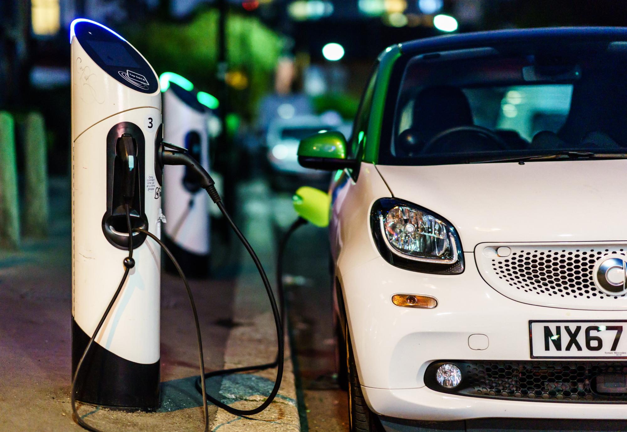 Car plugged into EV charge point on the road side