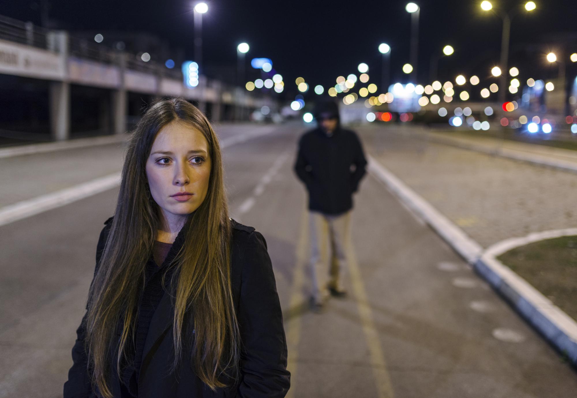 Woman walking alone with man walking behind