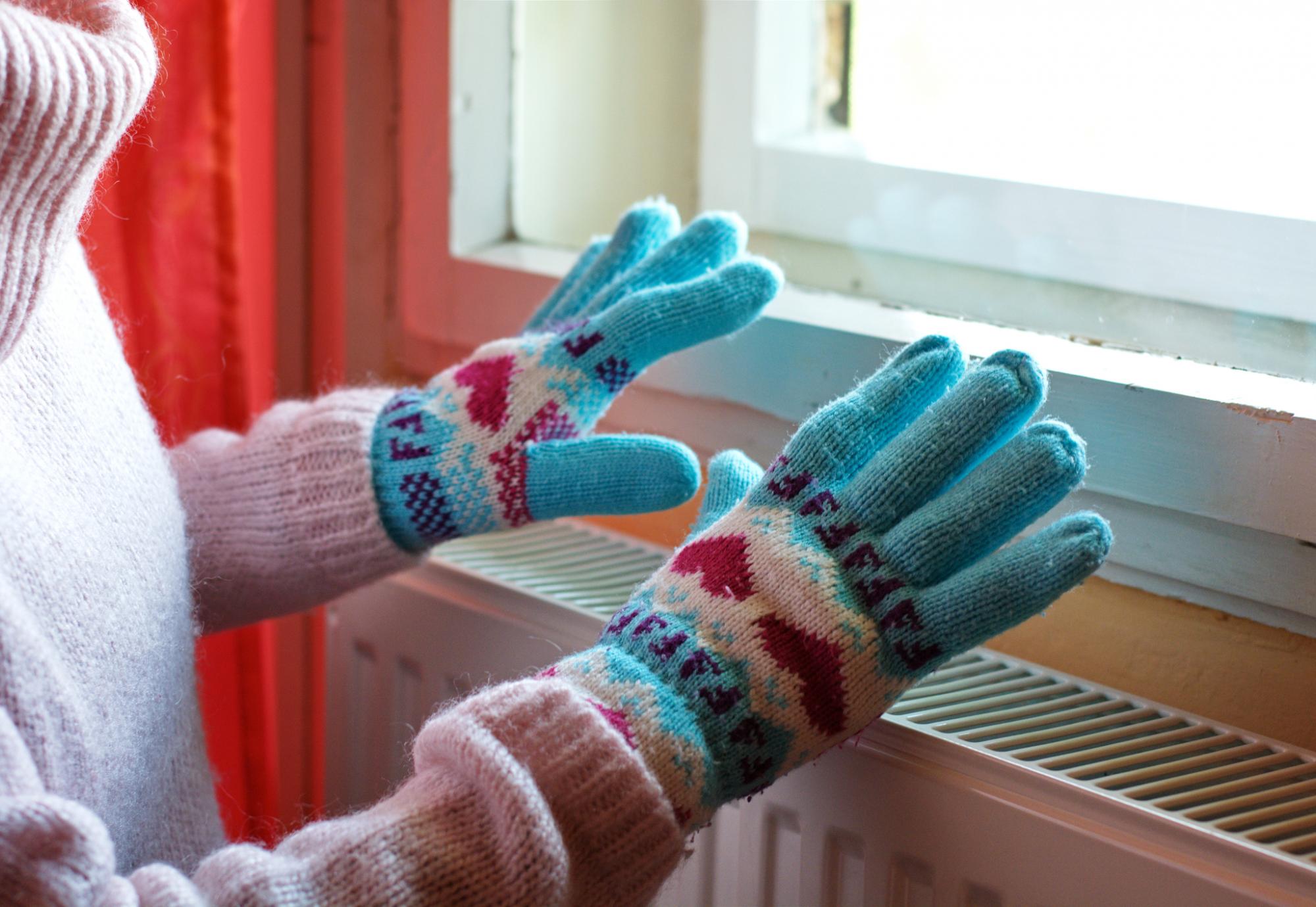 Person wearing gloves over radiator