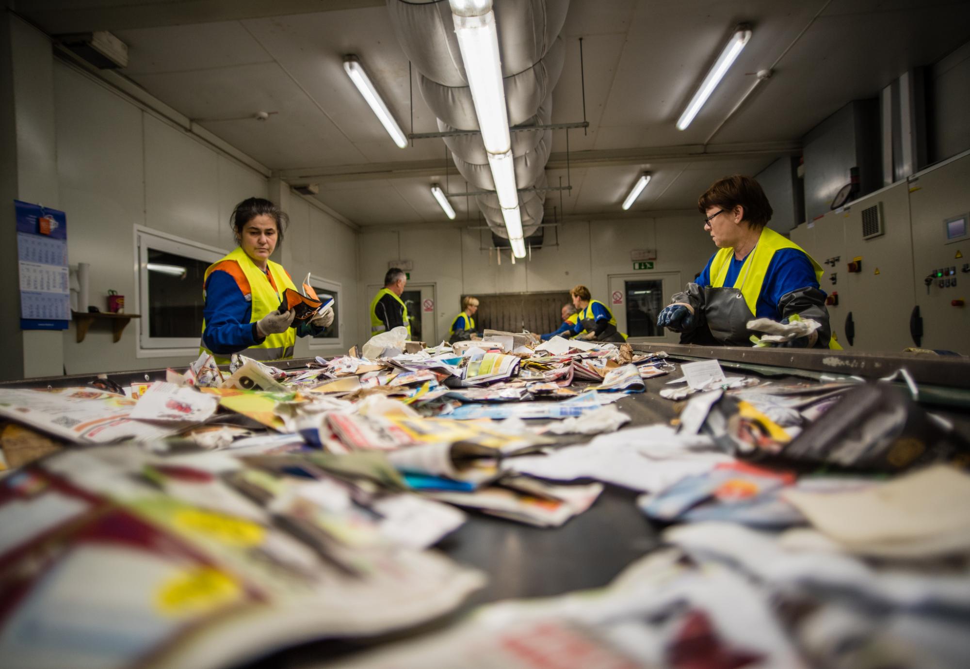 Recycling centre workers sorting out waste