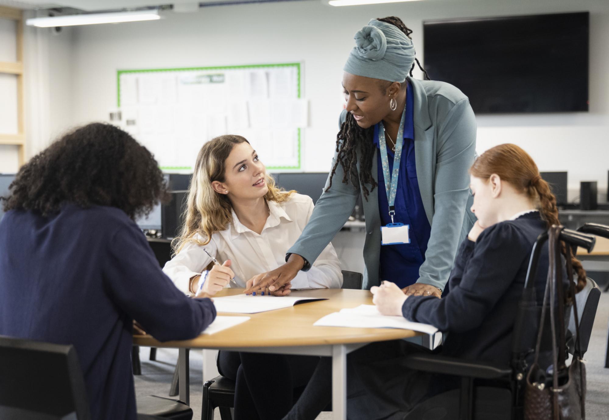 A female teacher helps students with their work