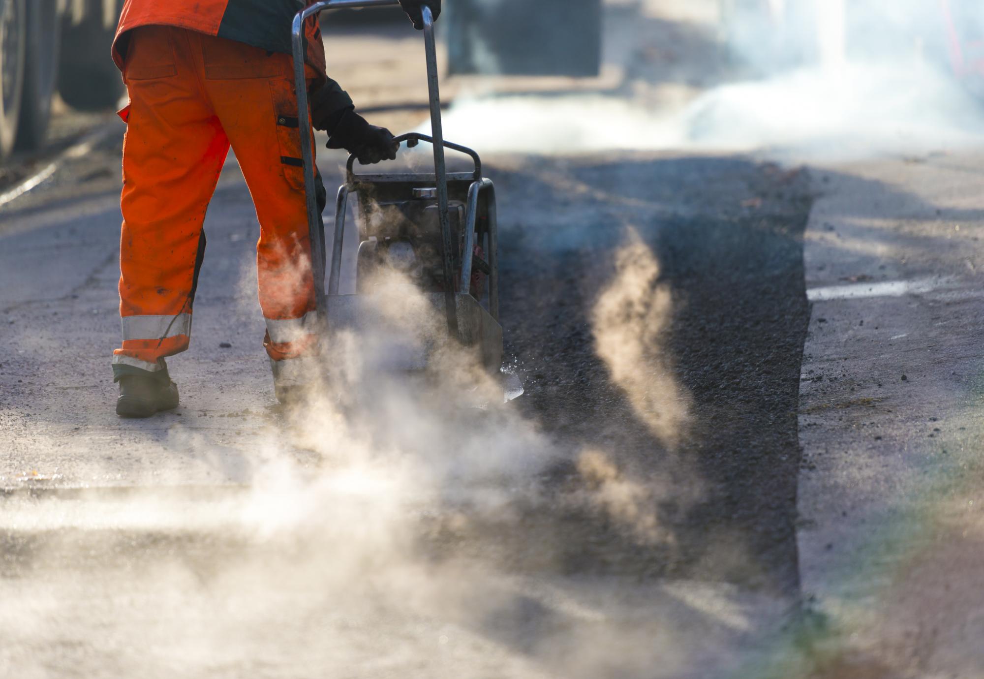 Road maintenance worker resurfacing tarmac