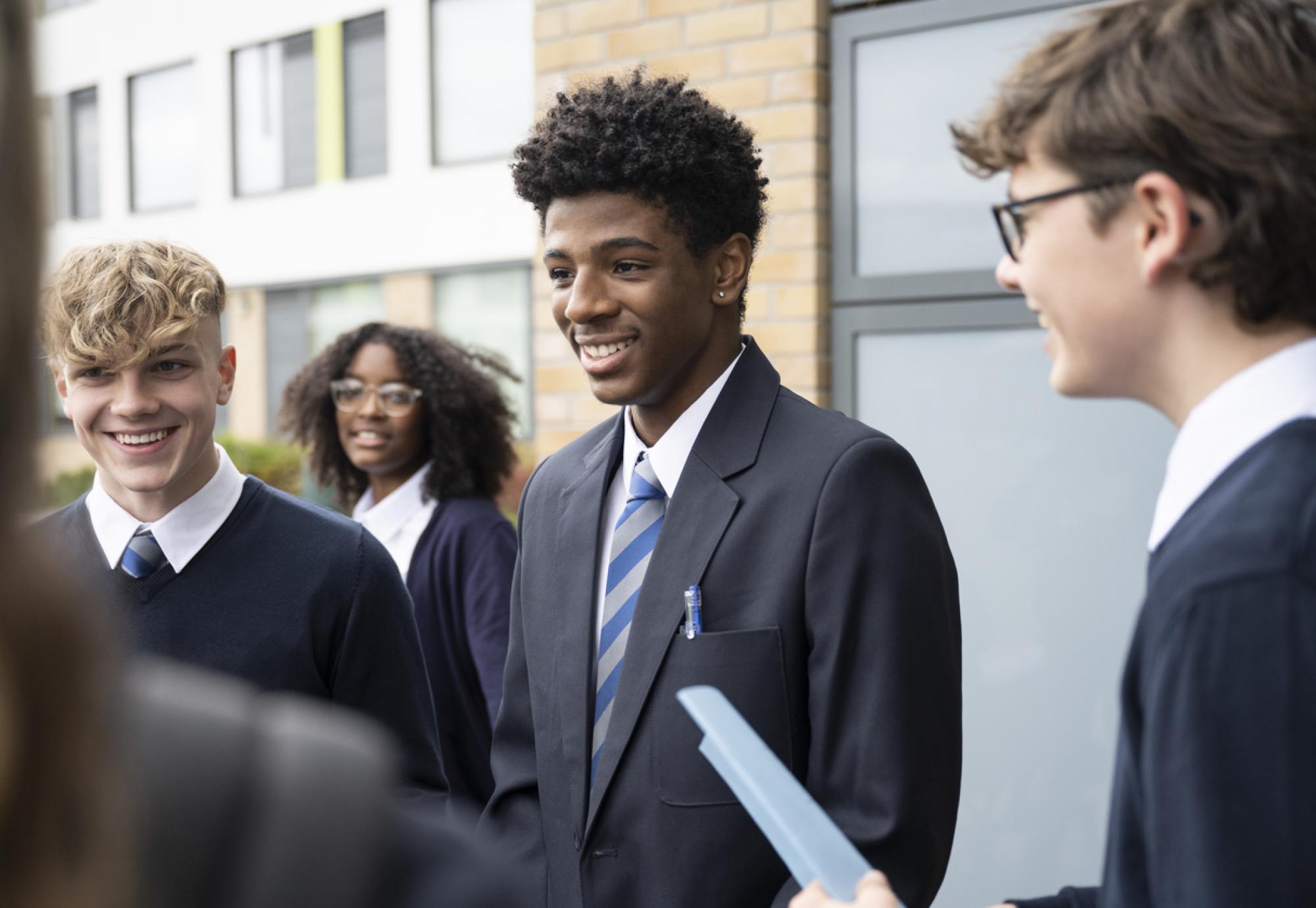 A diverse set of secondary school pupils stood outside a classroom 