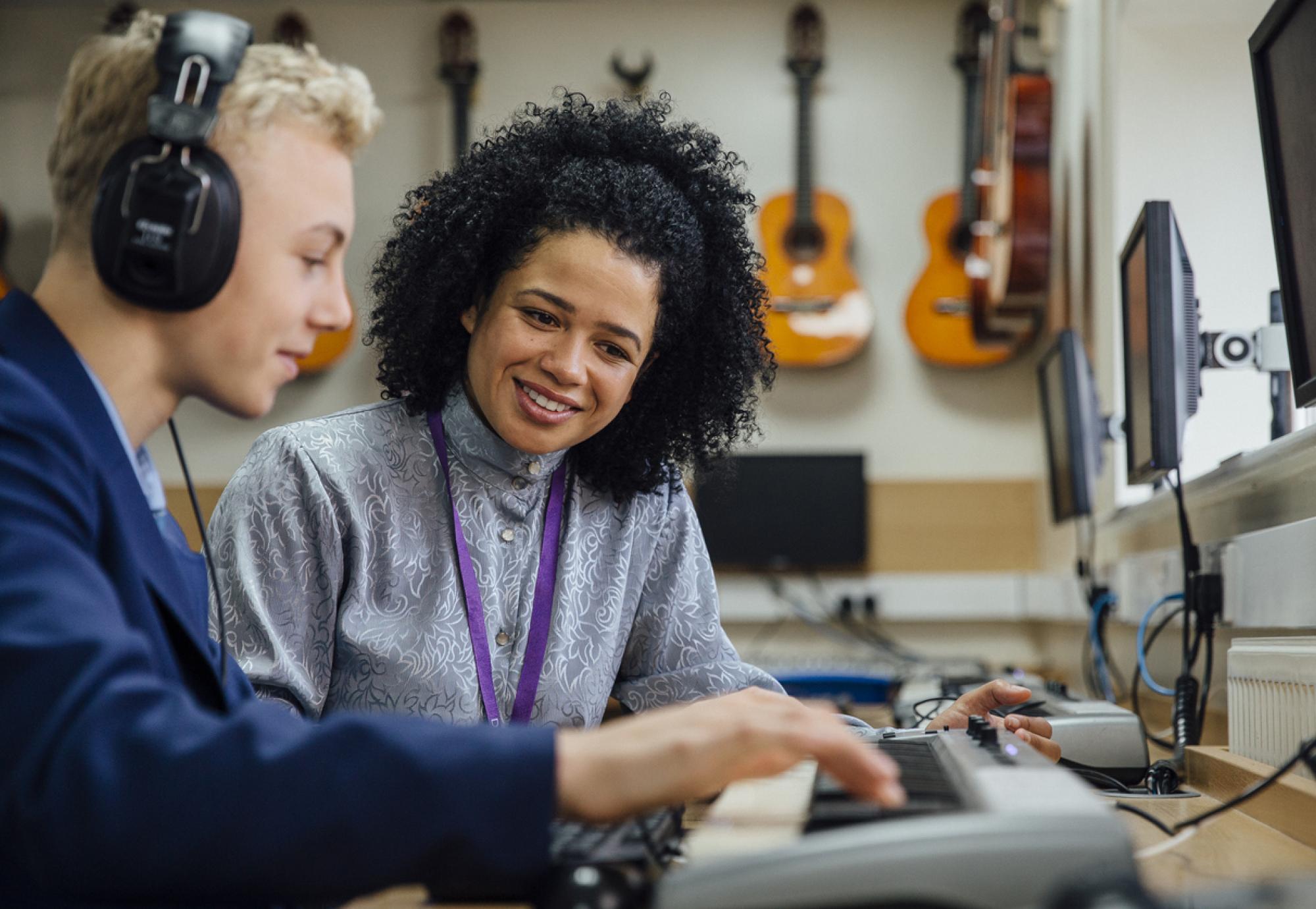 A teacher helping a male student learn to play the keyboard