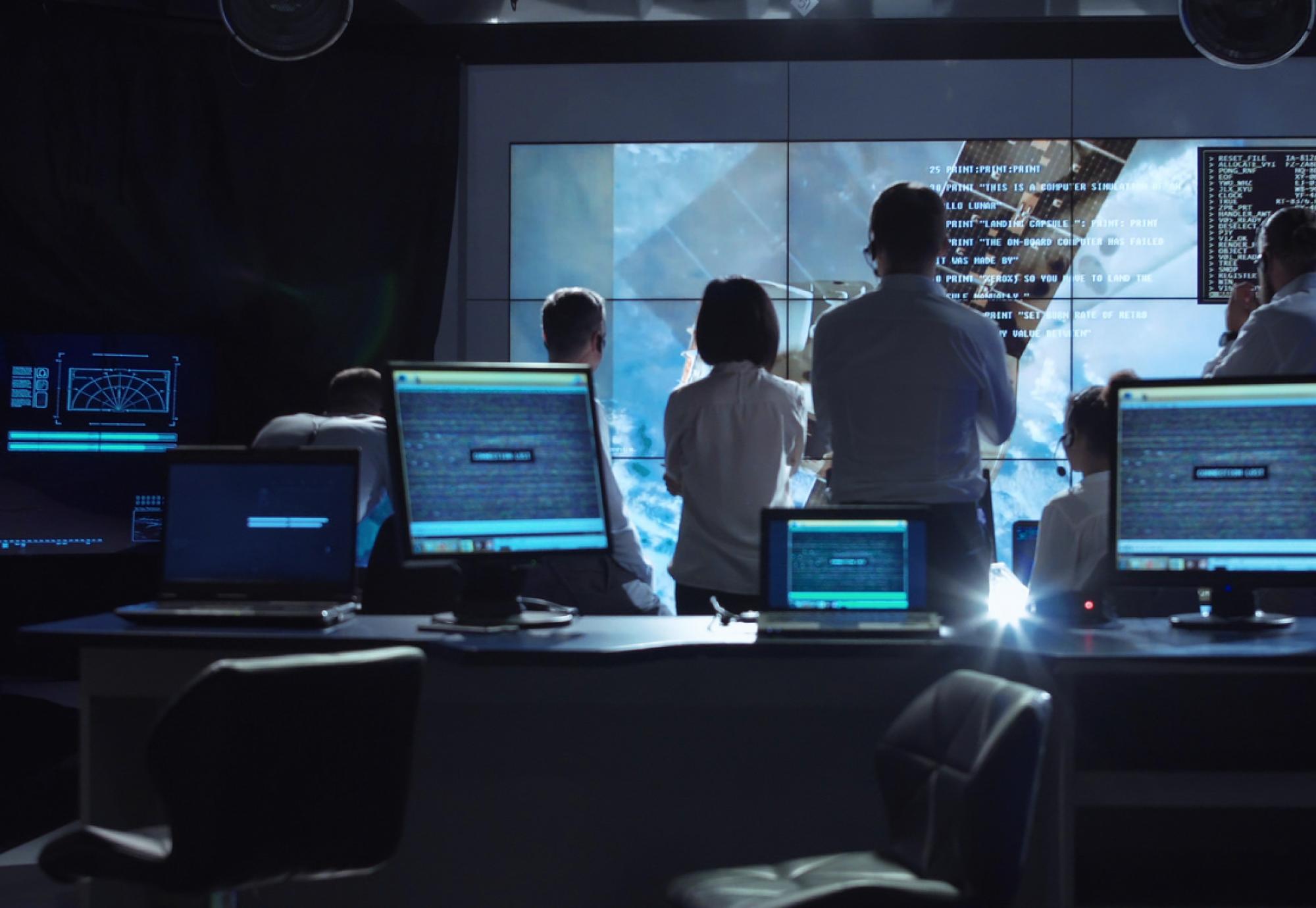 A group of people gather round a big screen whilst working on a digital project