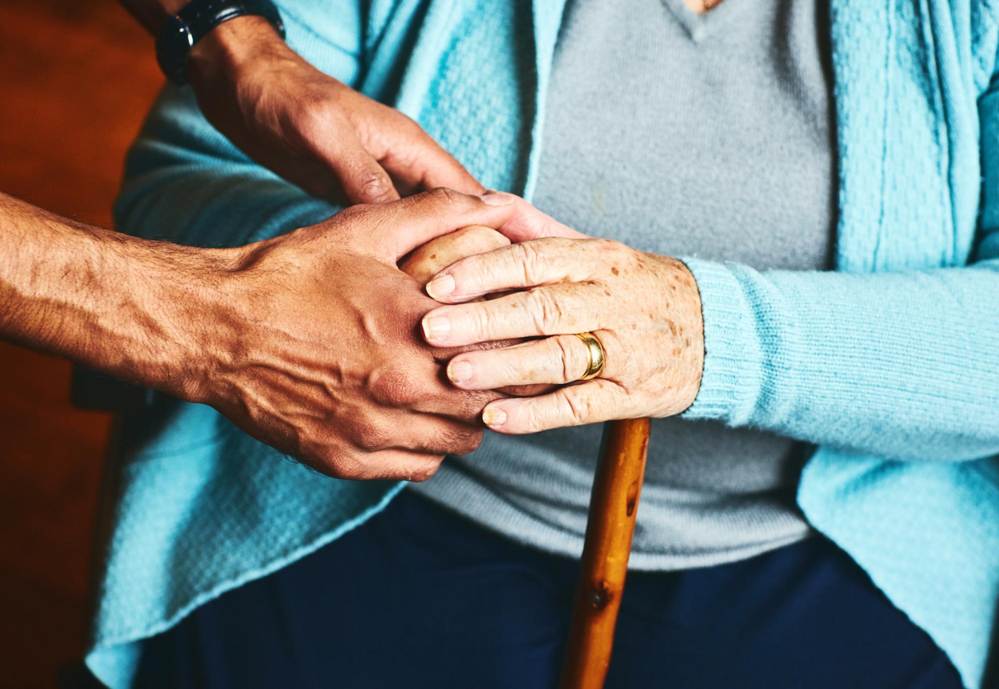 A carer holds hands with an older person