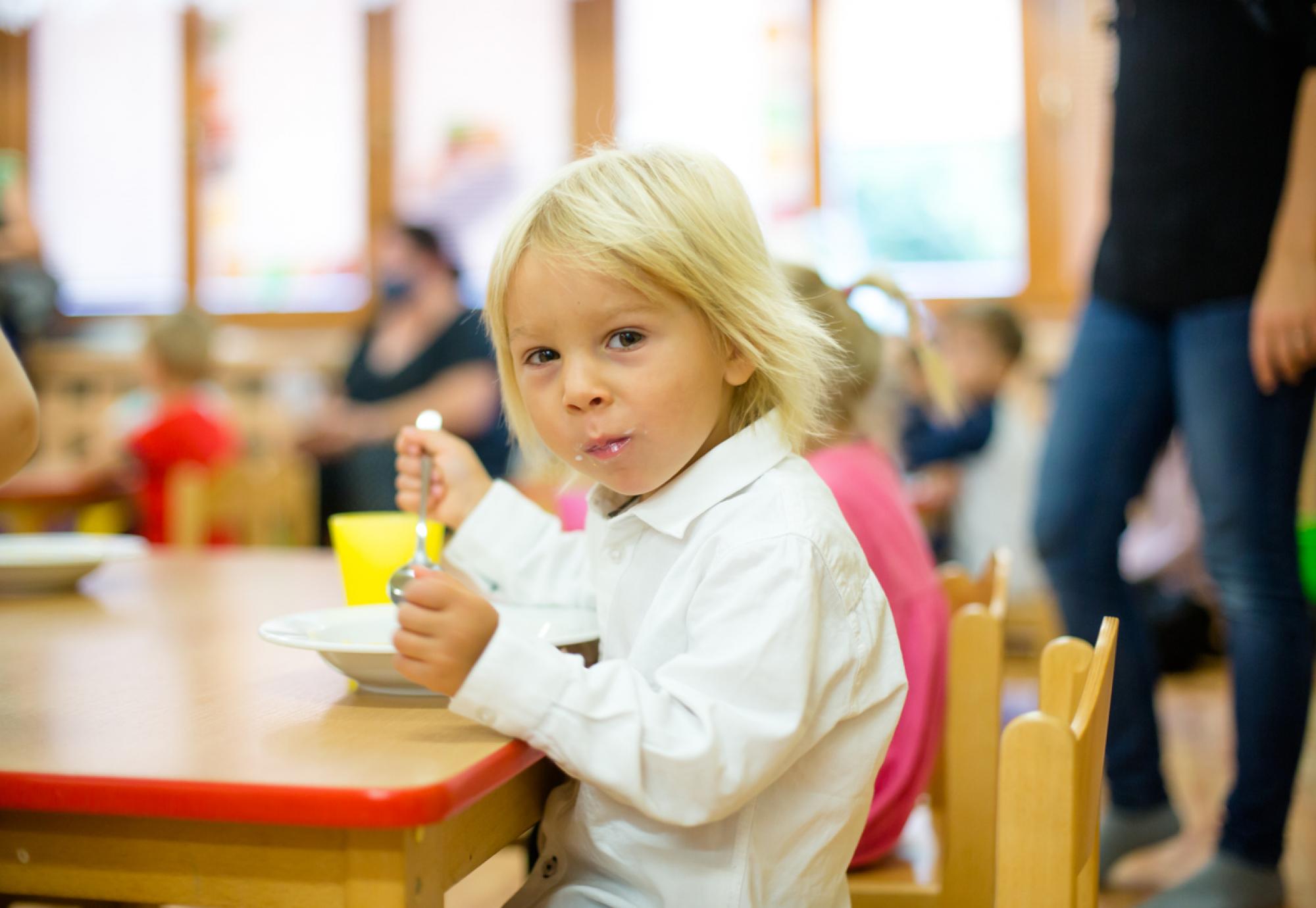 A child sits at school and eats lunch