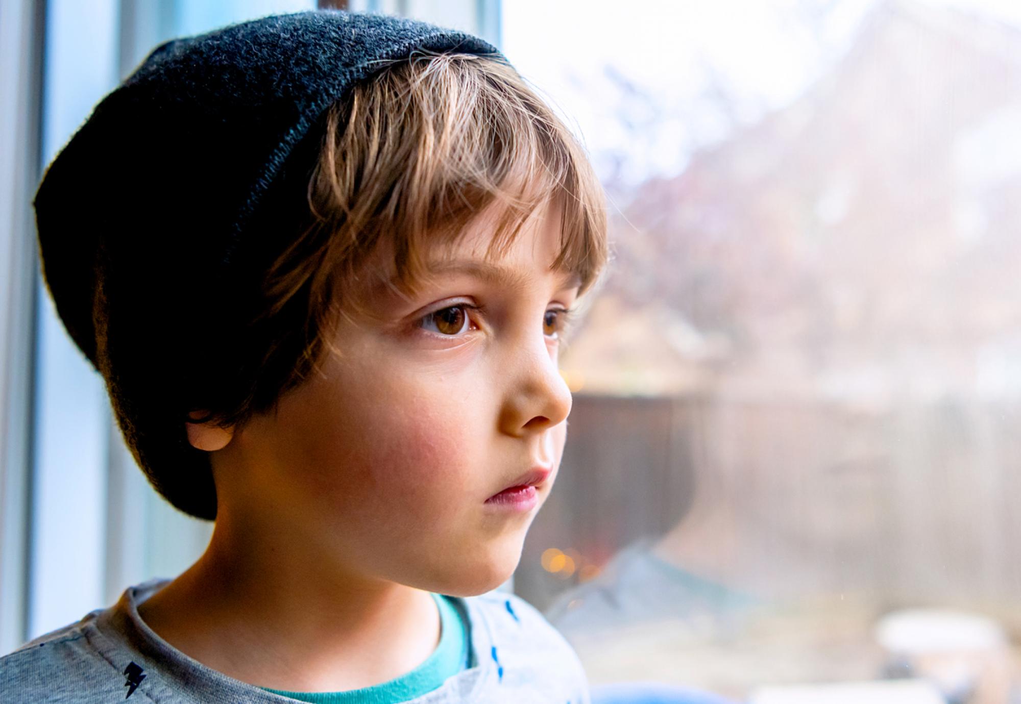 Pensive looking child looks out of a window