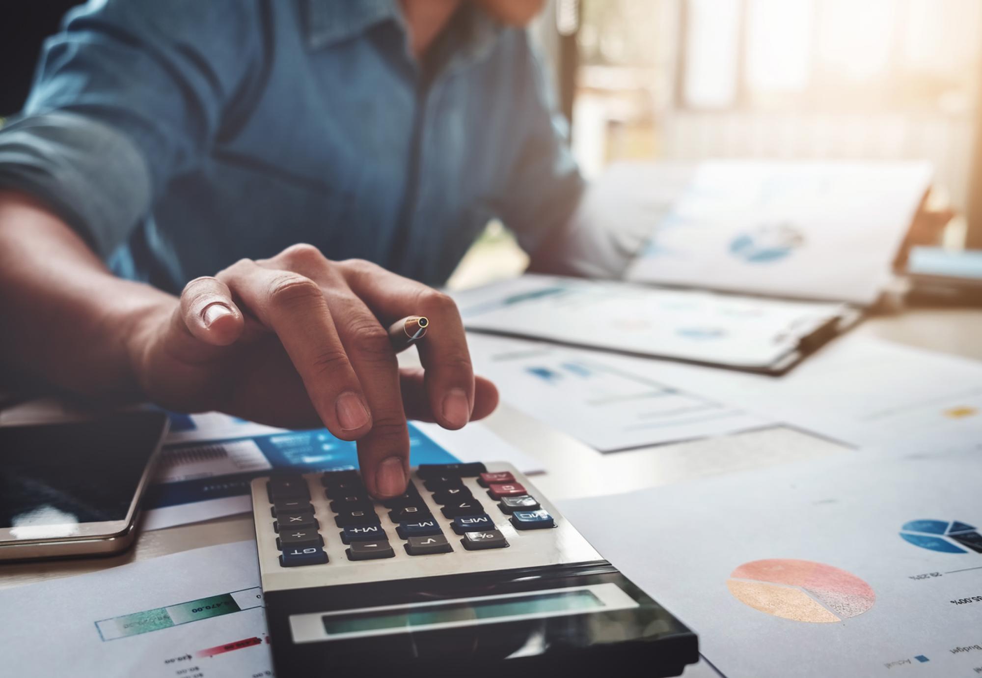 An unidentifiable man working out a budget with a calculator