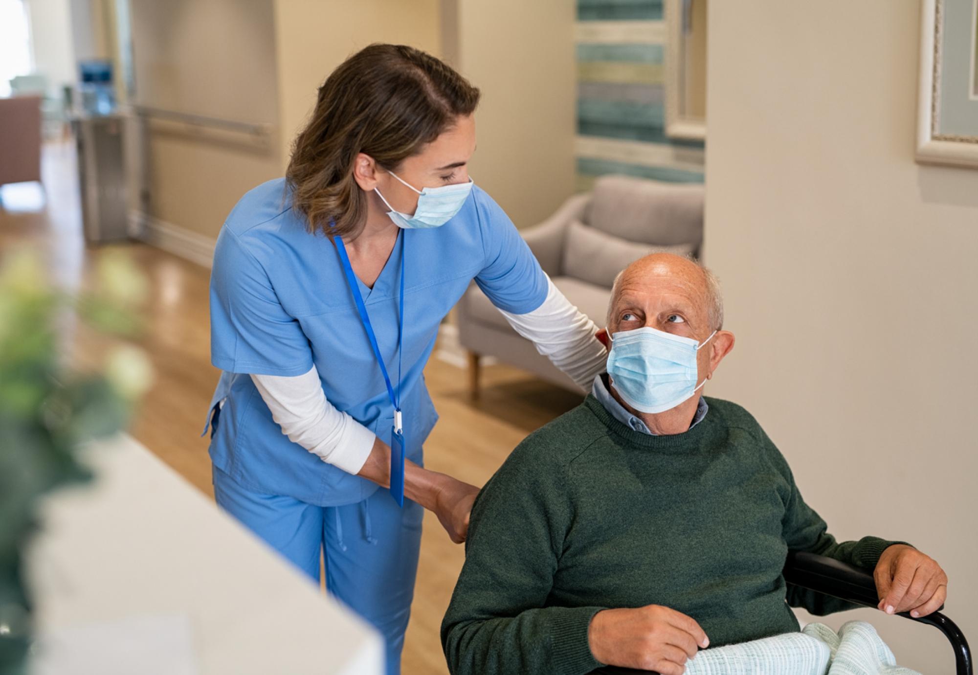 A nurse helping an older male in a wheelchair