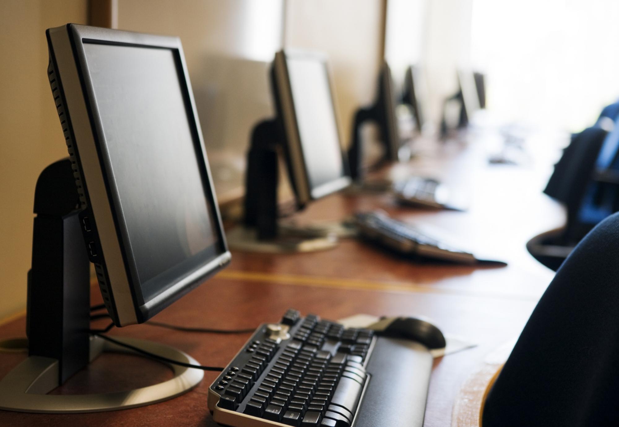 Row of modern screens and keyboards in a computer lab