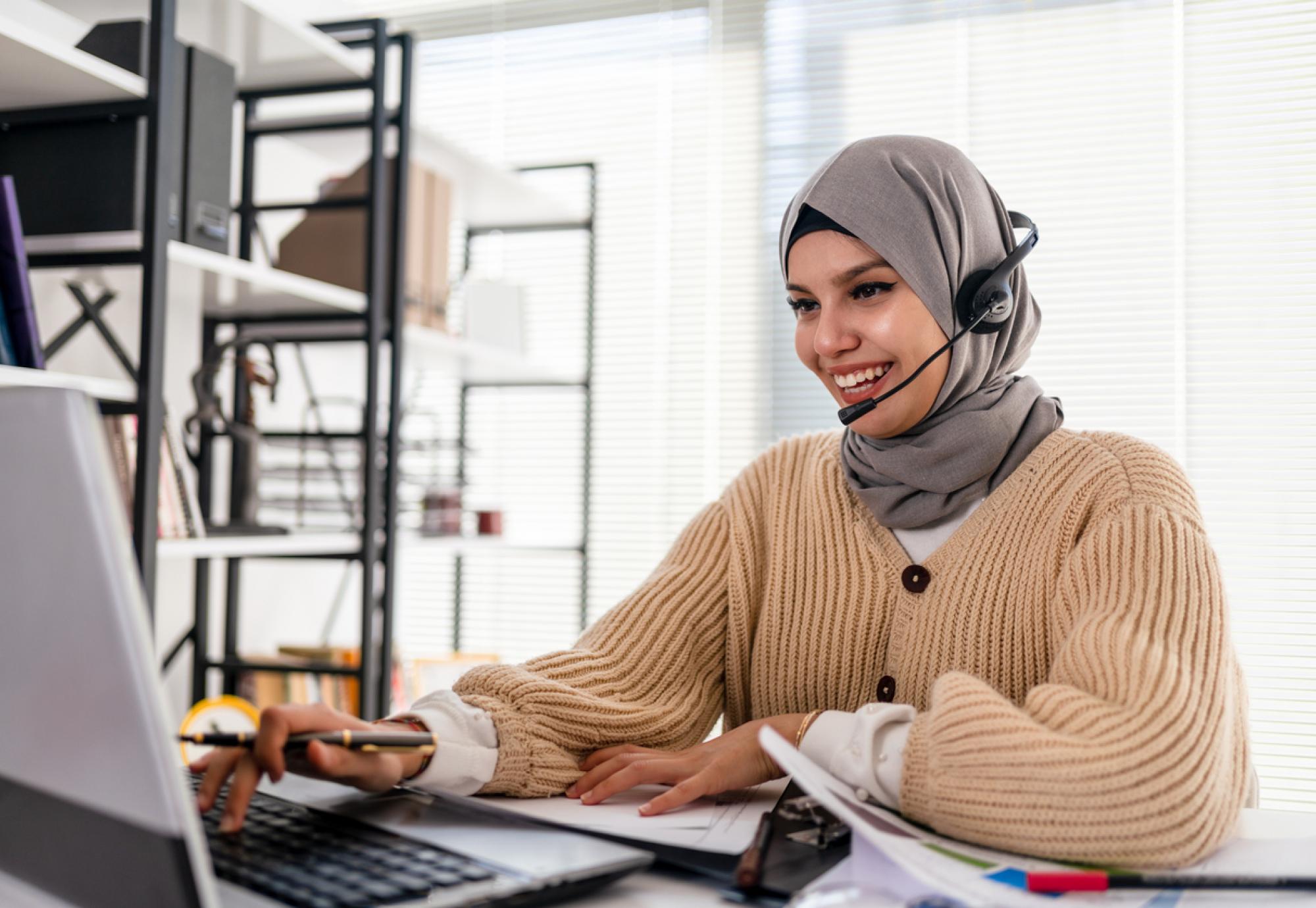 Lady in a hijab working at a computer in an office