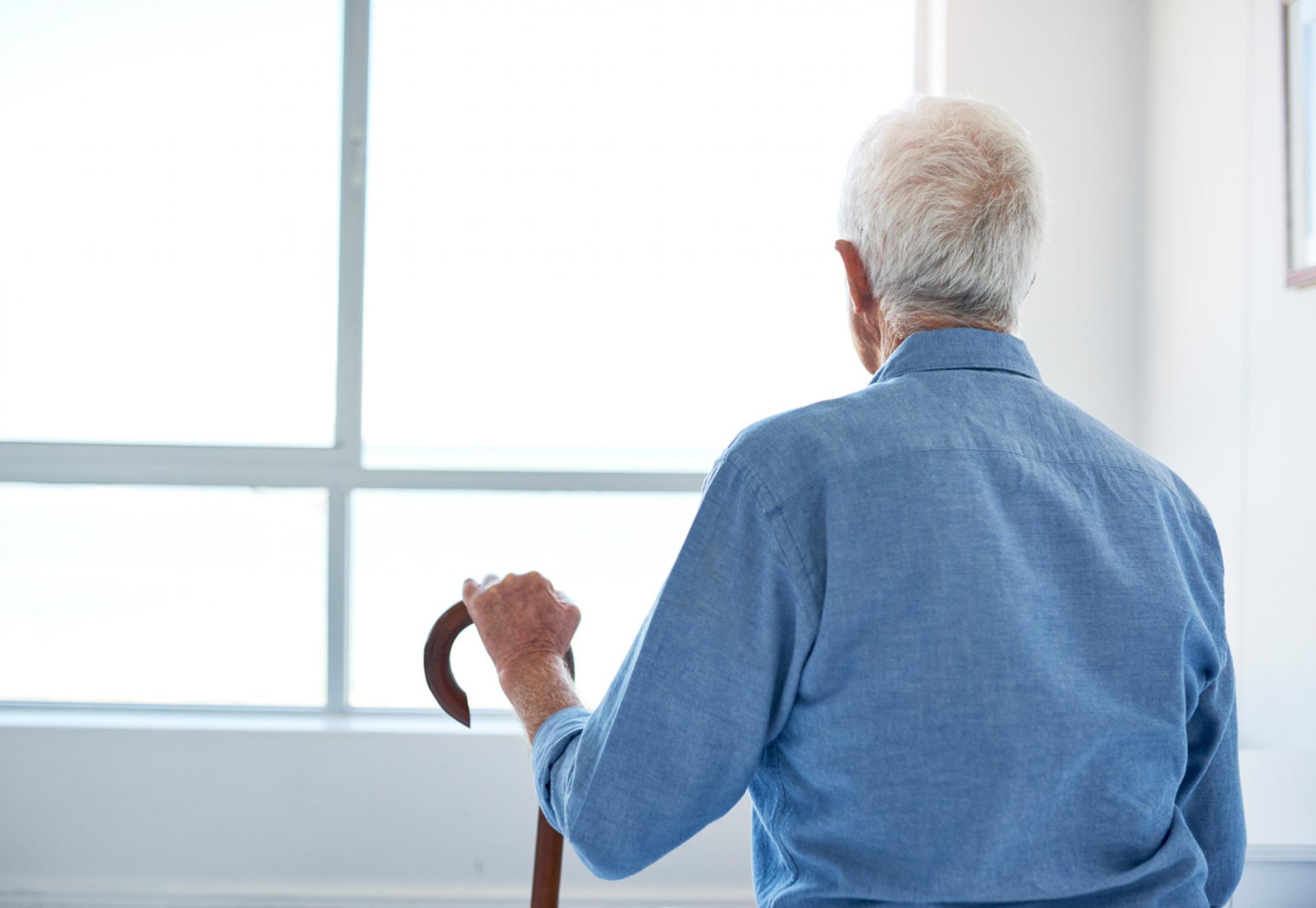 Old man with dementia looks out of a window.