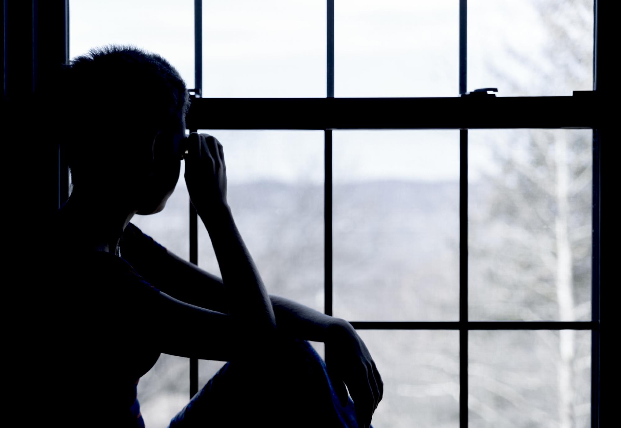 A homeless child looks out of the window of a hostel