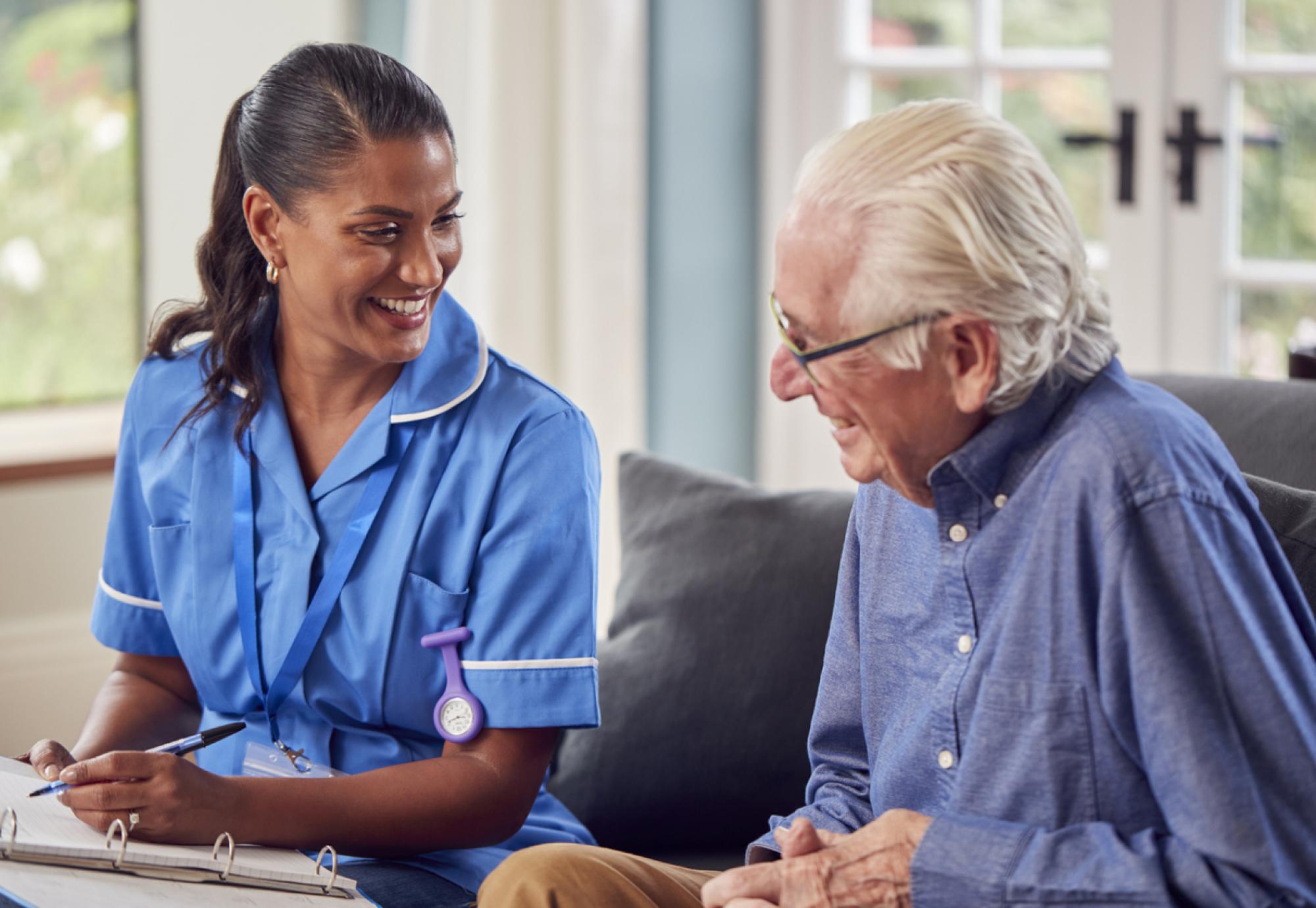 Older man talking to a nurse in his home