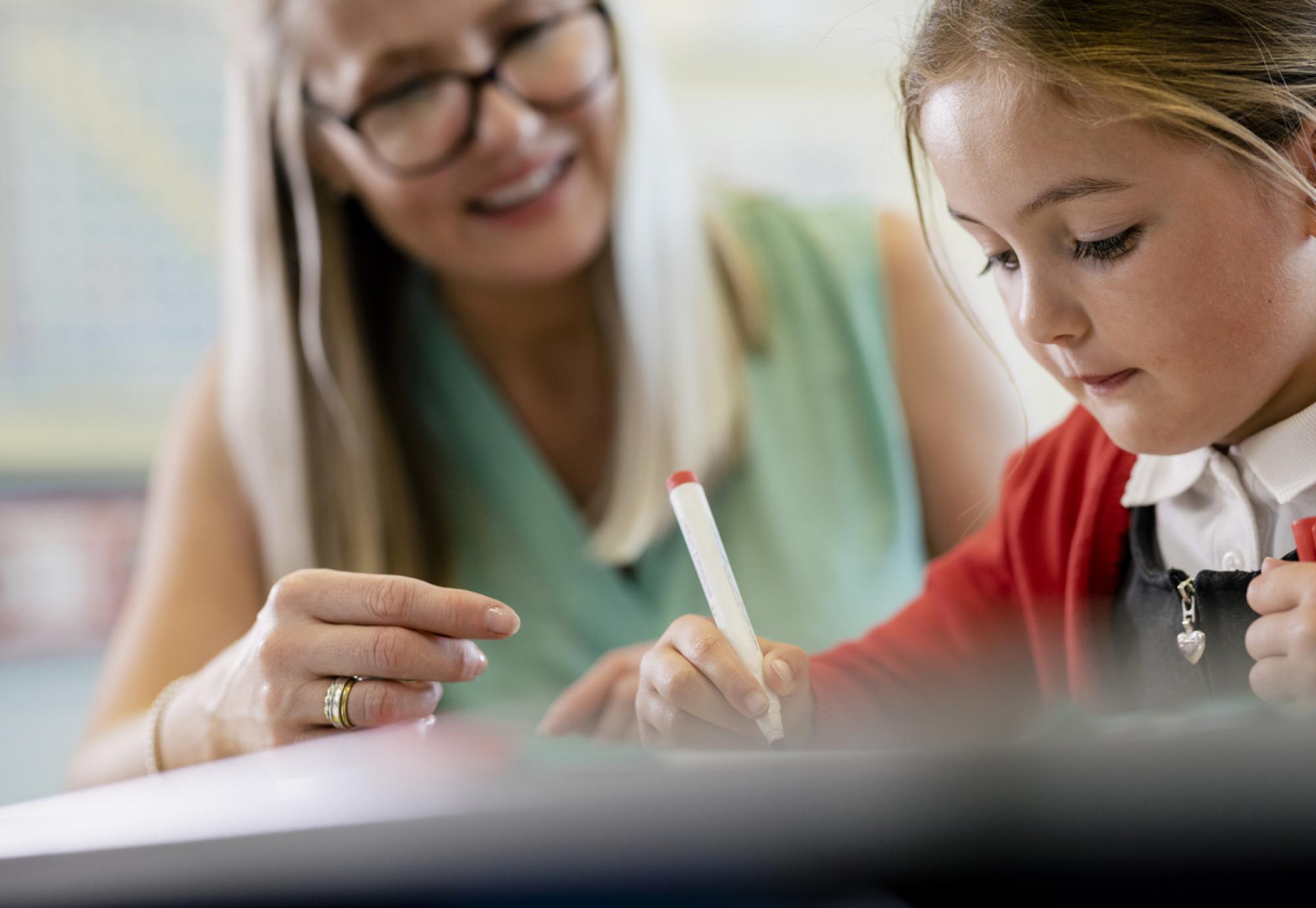 Young girl sat in classroom with her teacher