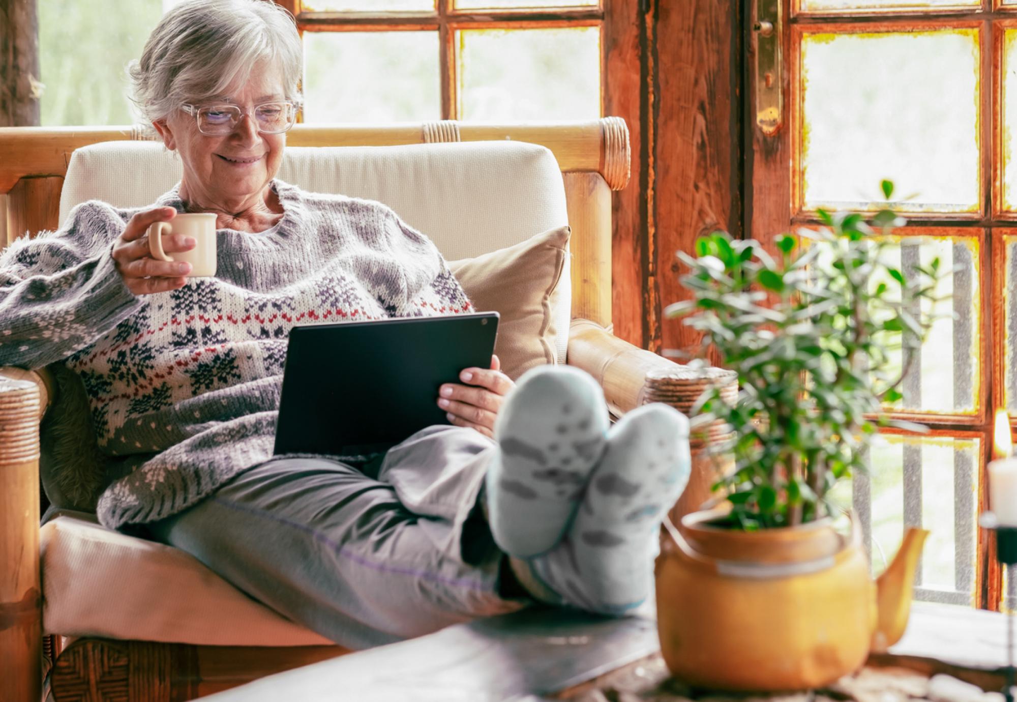 Older lady sat at home using a tablet