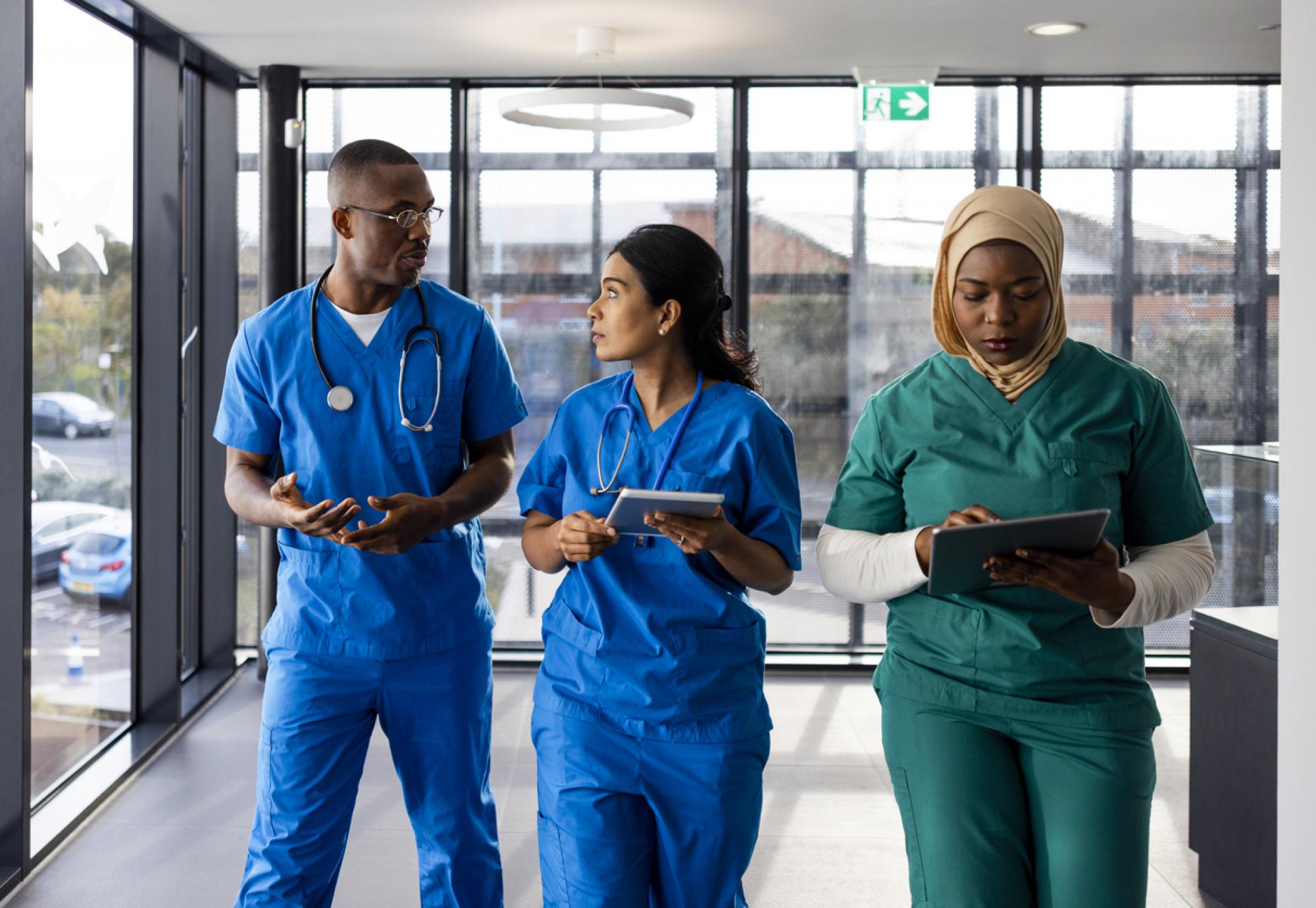 Three healthcare workers walking down a corridor in an English hospital