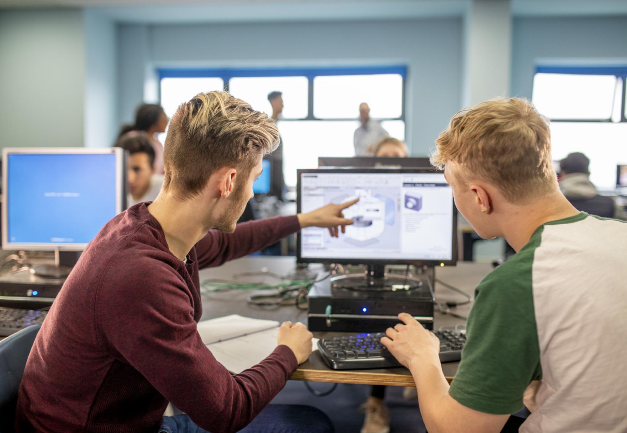 Two young men work together on a project on a computer