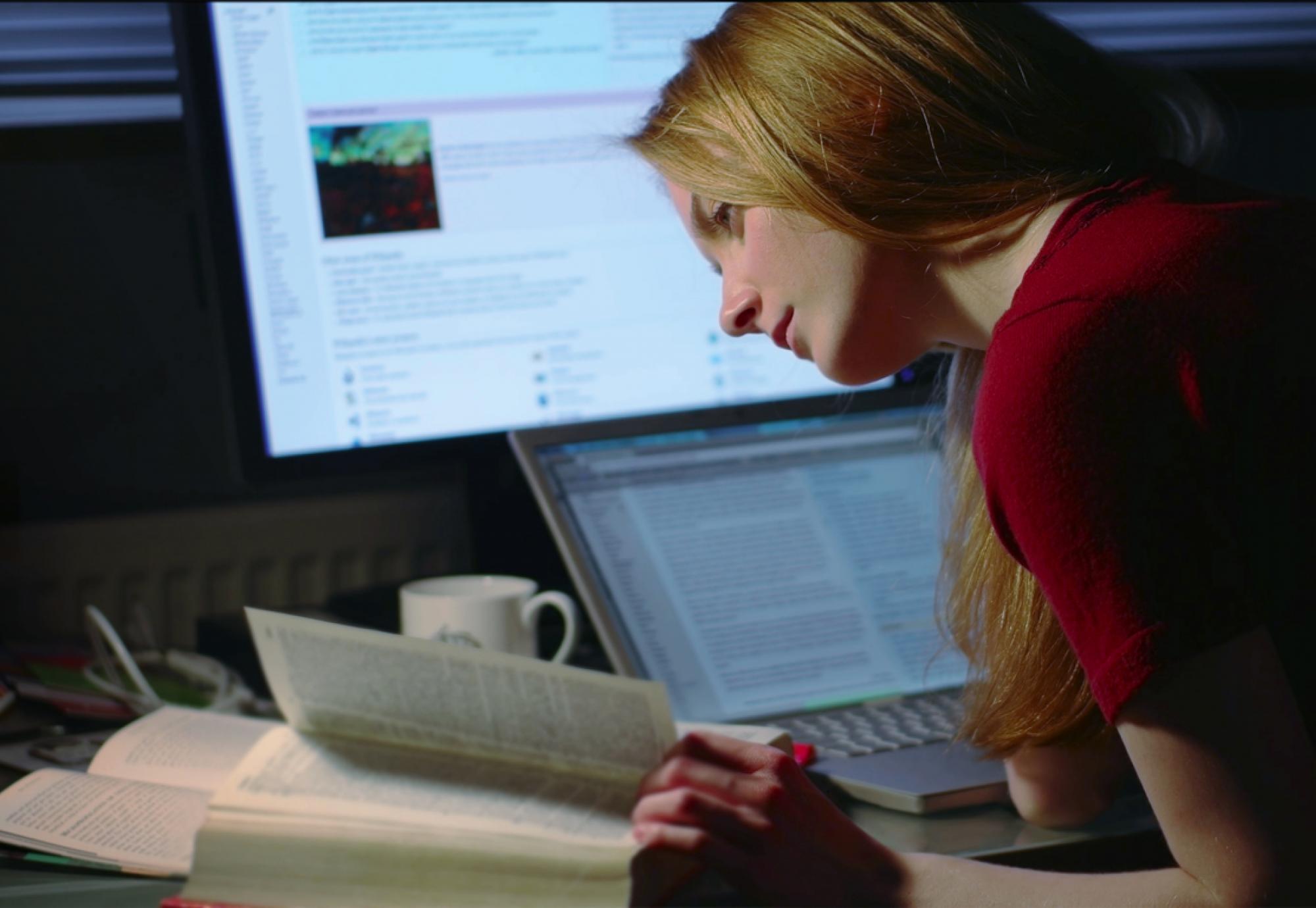 A girl studying/working at a desk with two computers