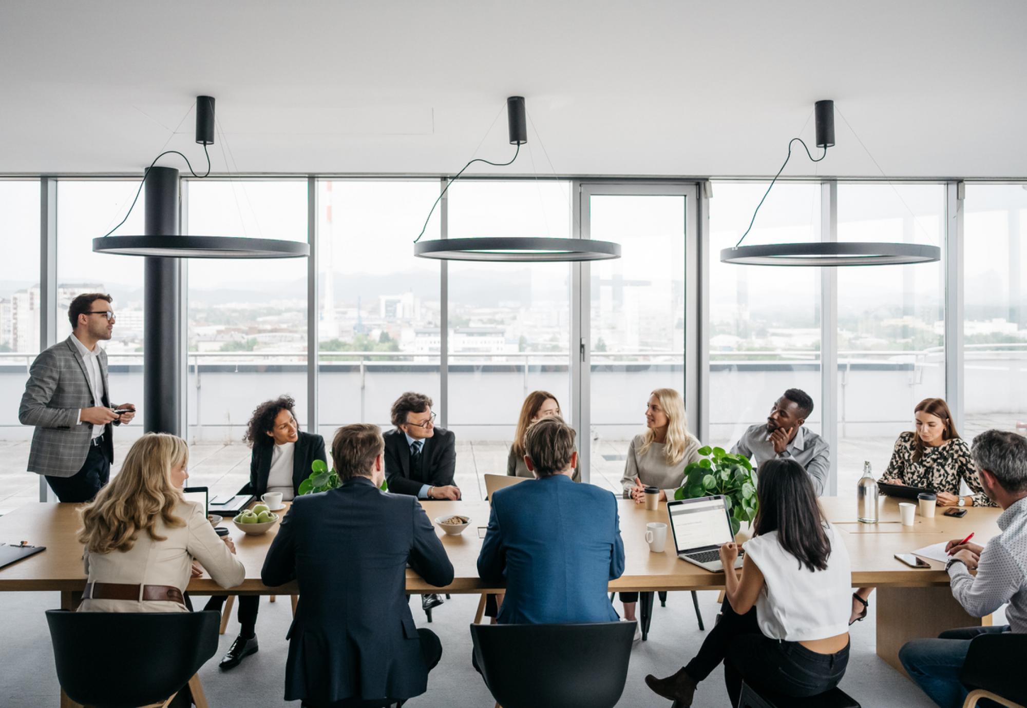 A photo of a business meeting in a modern office with large windows.