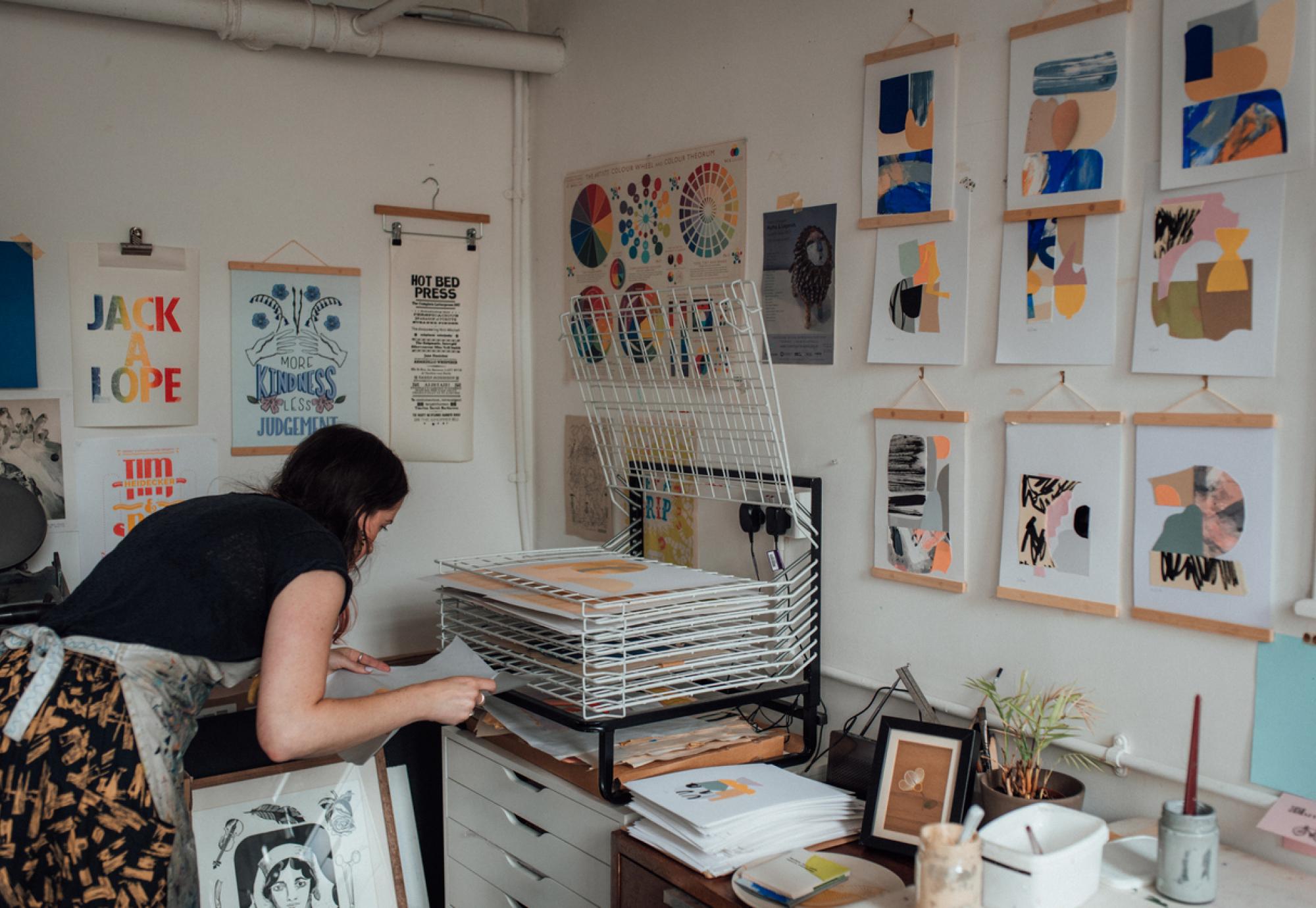 An artist laying prints to dry on a rack