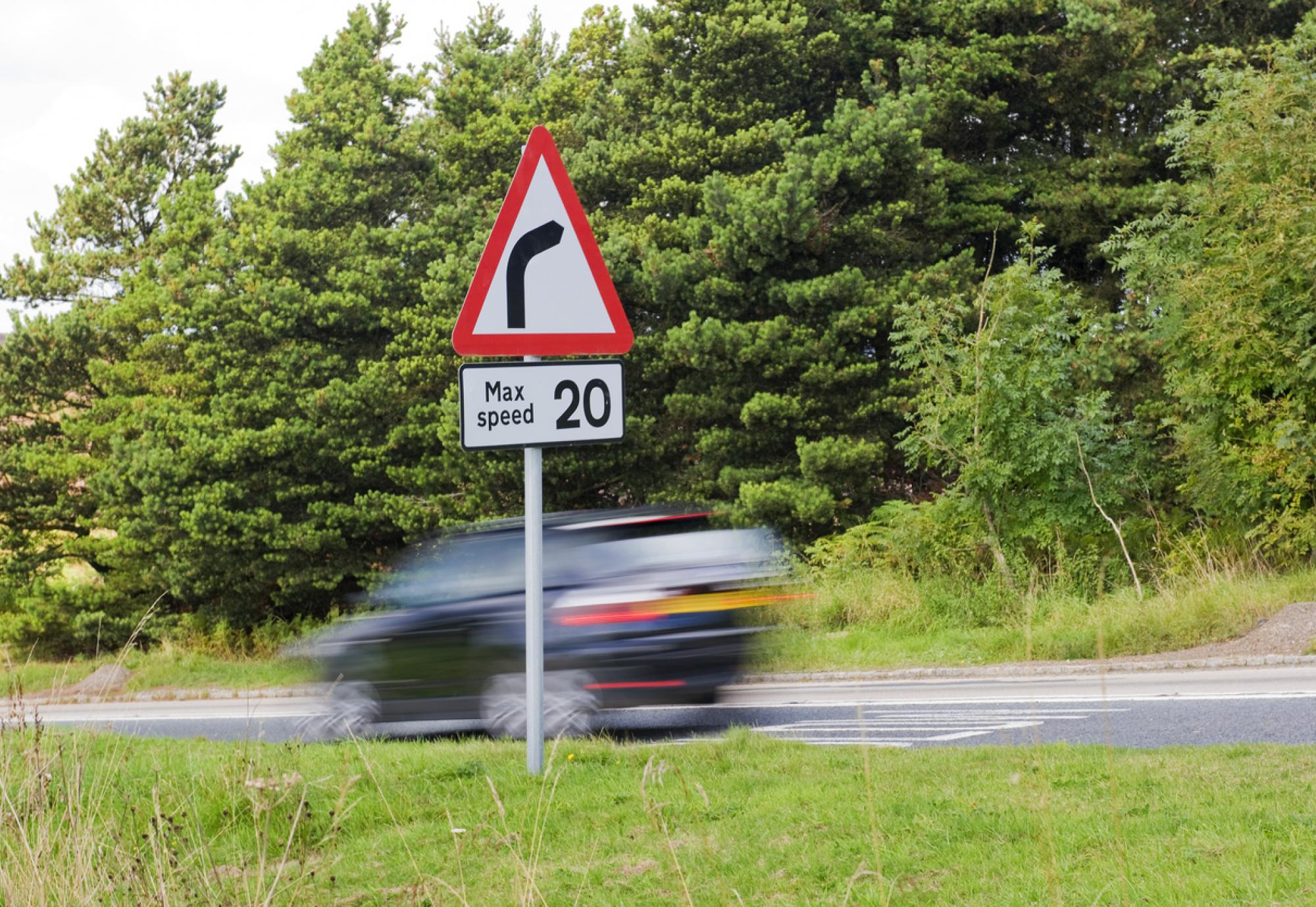 Speed limit sign as car drives past in the UK countryside