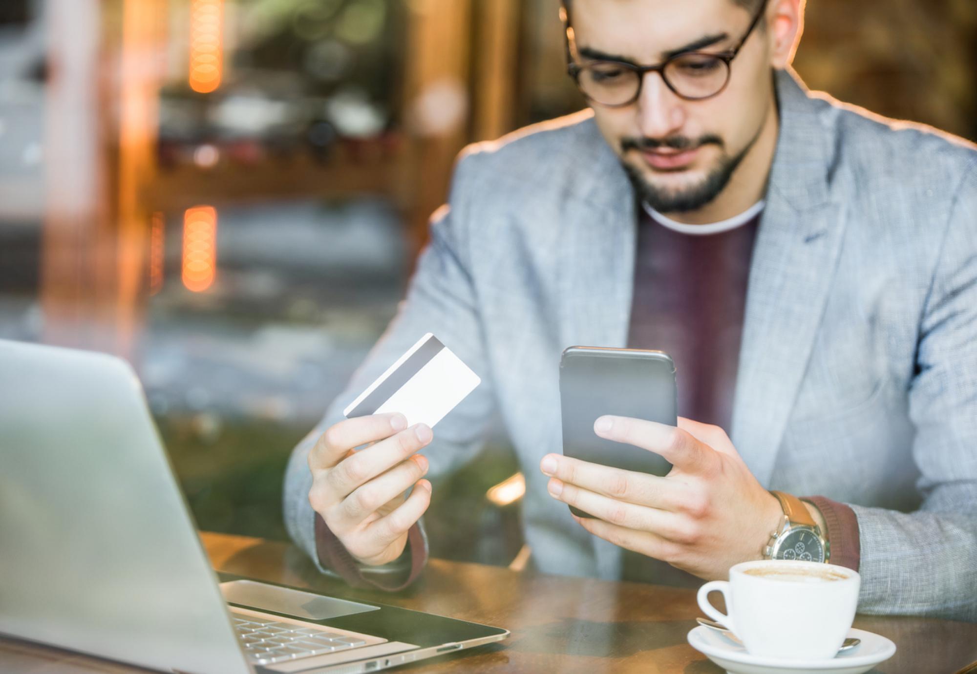 Young man using a credit card to invest online.