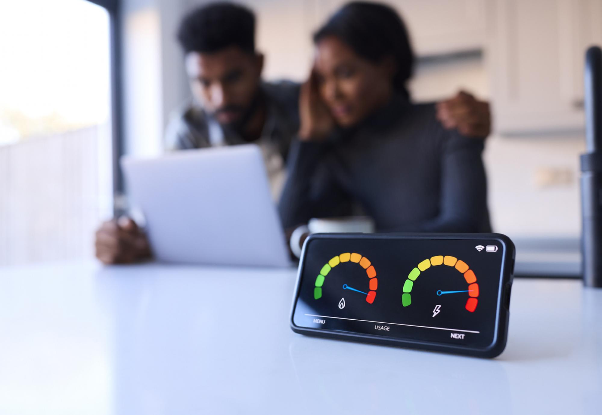 Couple looking anxious at laptop with smart energy meter in the foreground