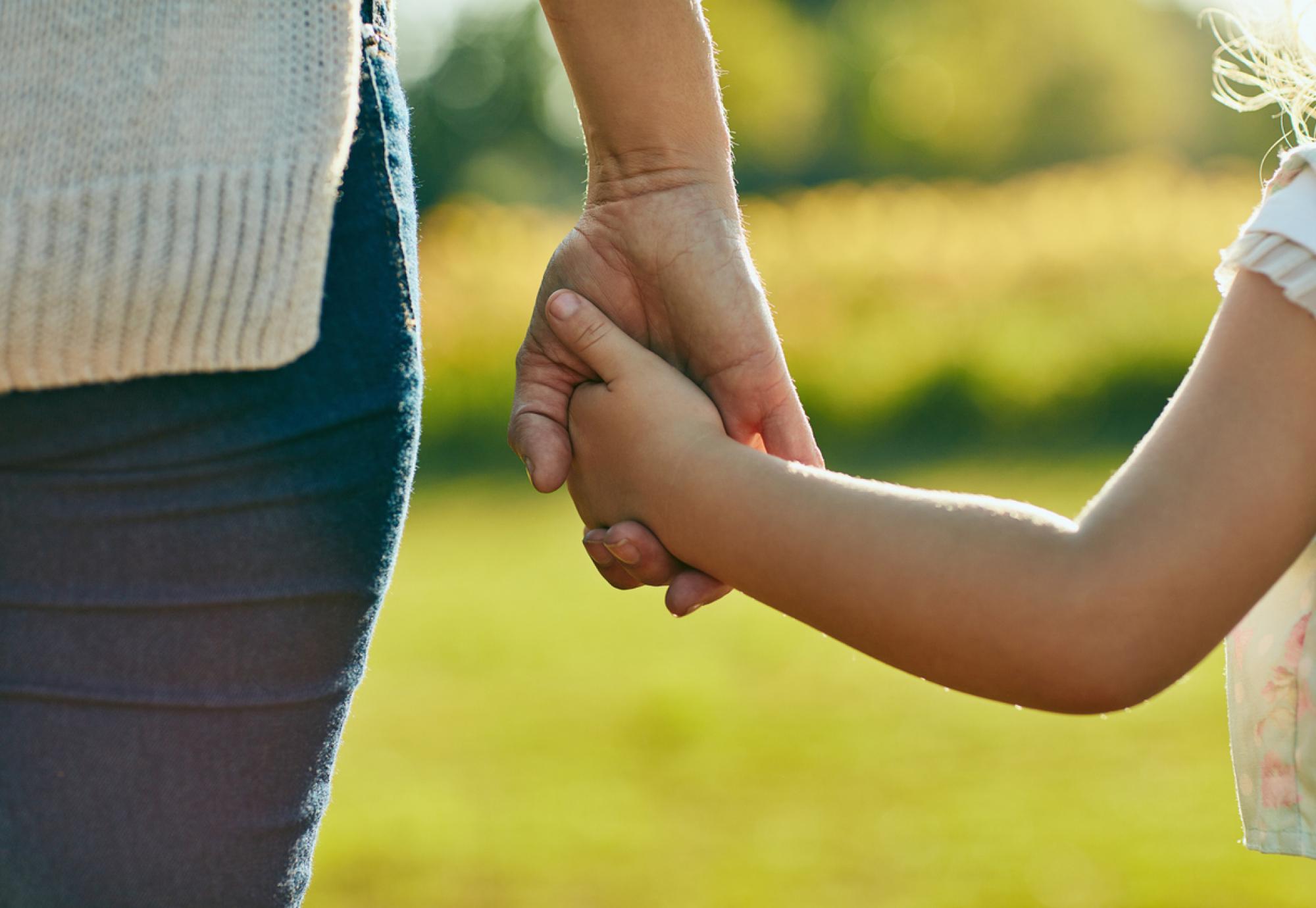 Woman and child holding hands on a sunny day