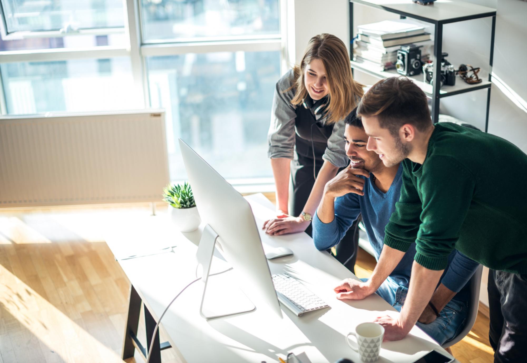 Three young people gathered round a computer