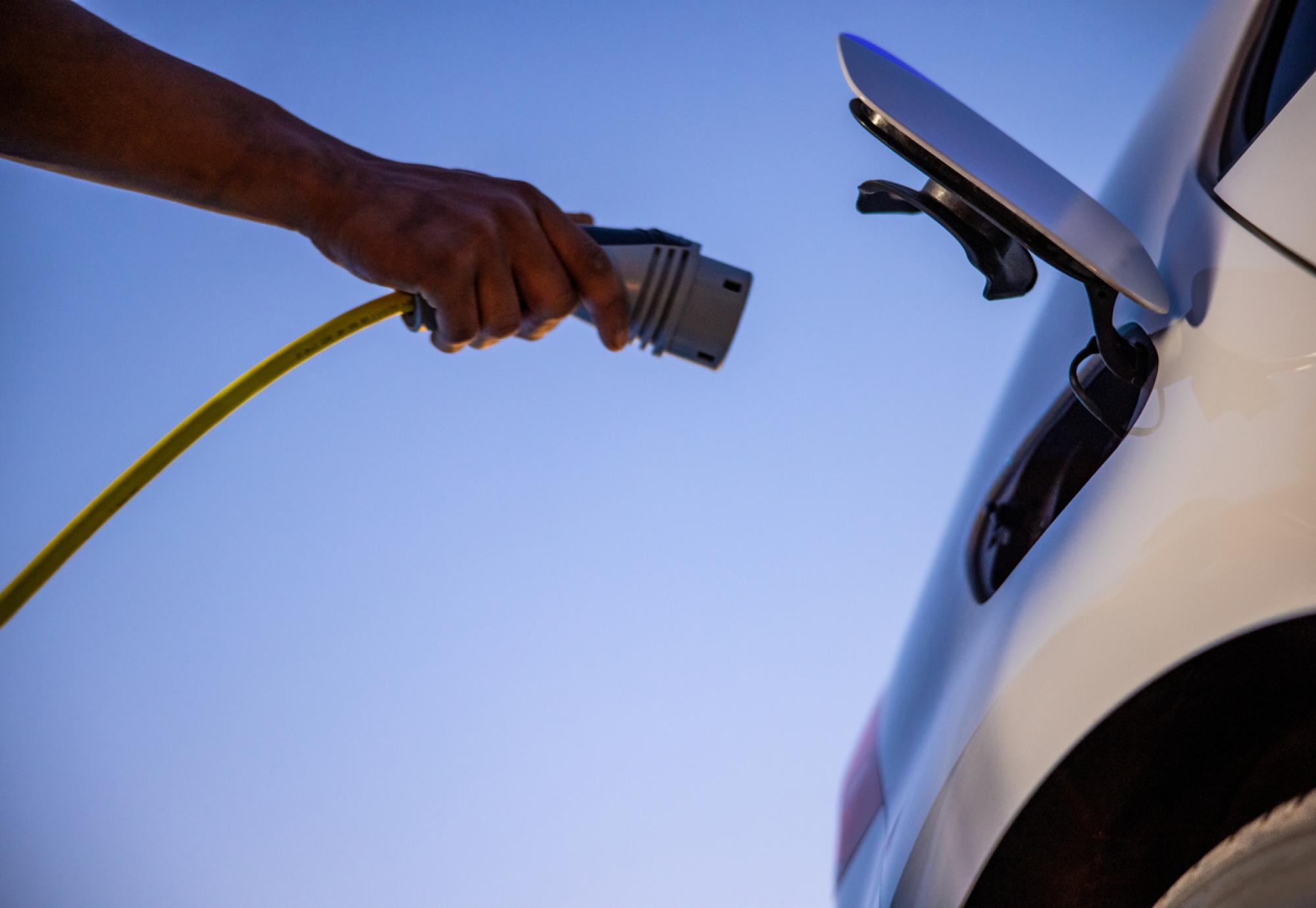 Person plugging an EV charger into an electric vehicle