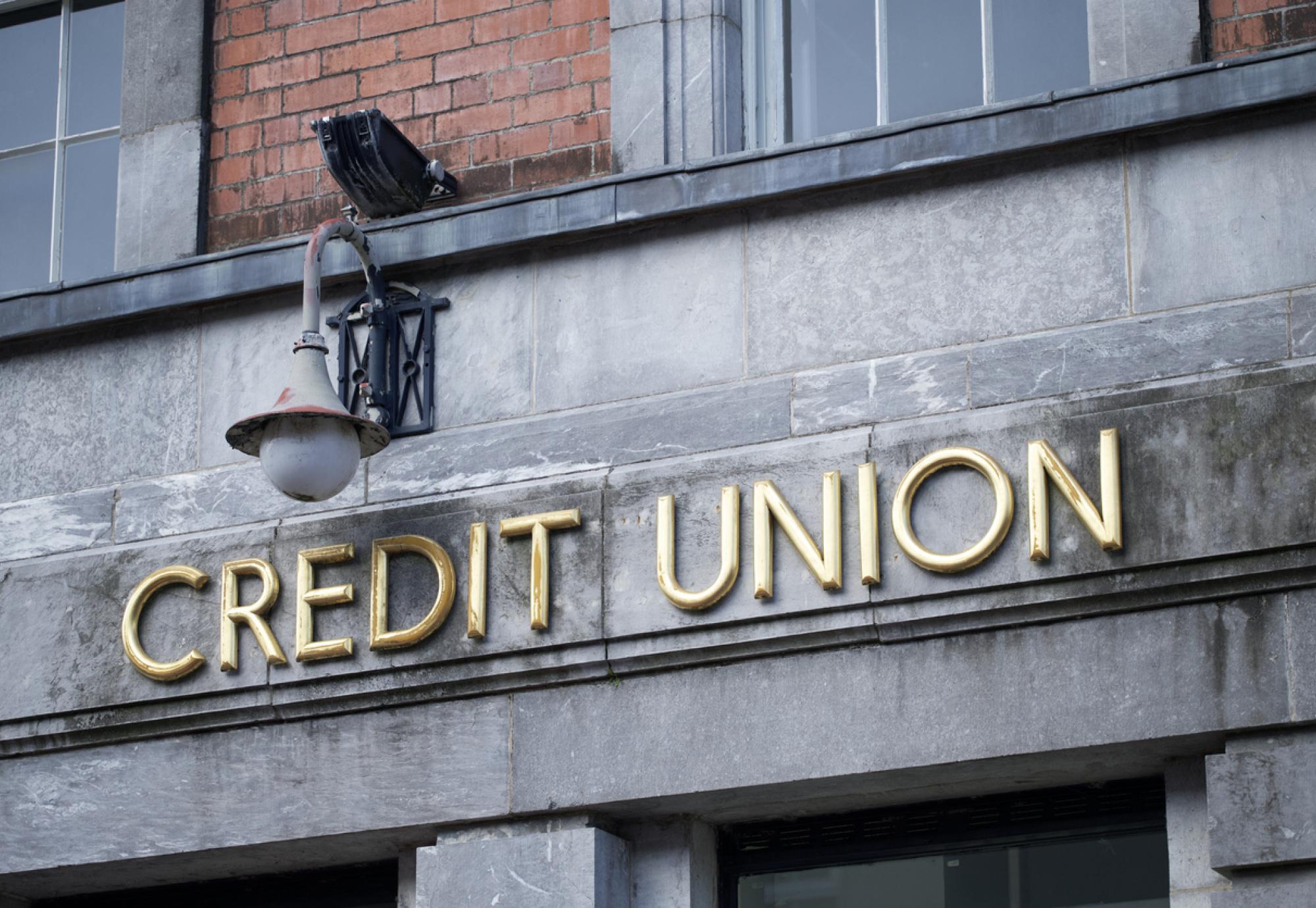 Sign of a credit union in gold writing on a stone wall