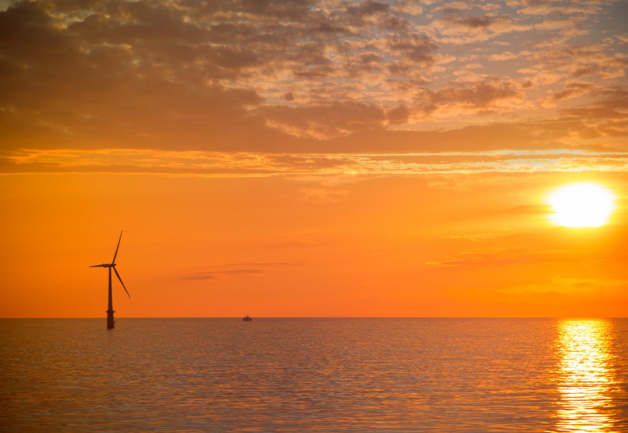 Sunset over the North Sea with a wind turbine in the distance