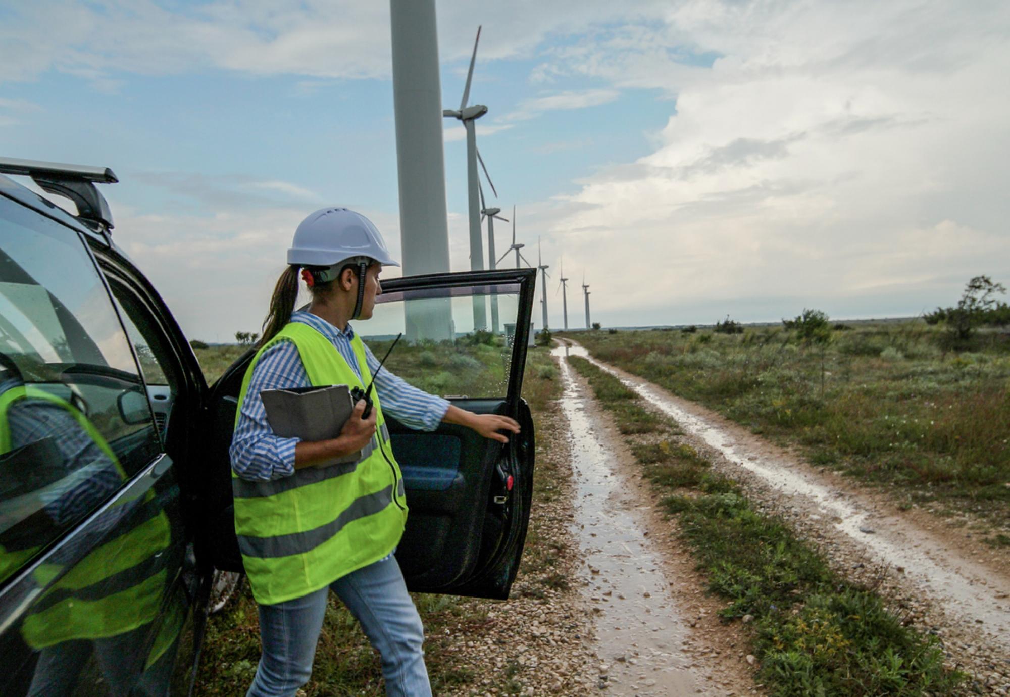 Woman getting out of a car at a group of wind turbines