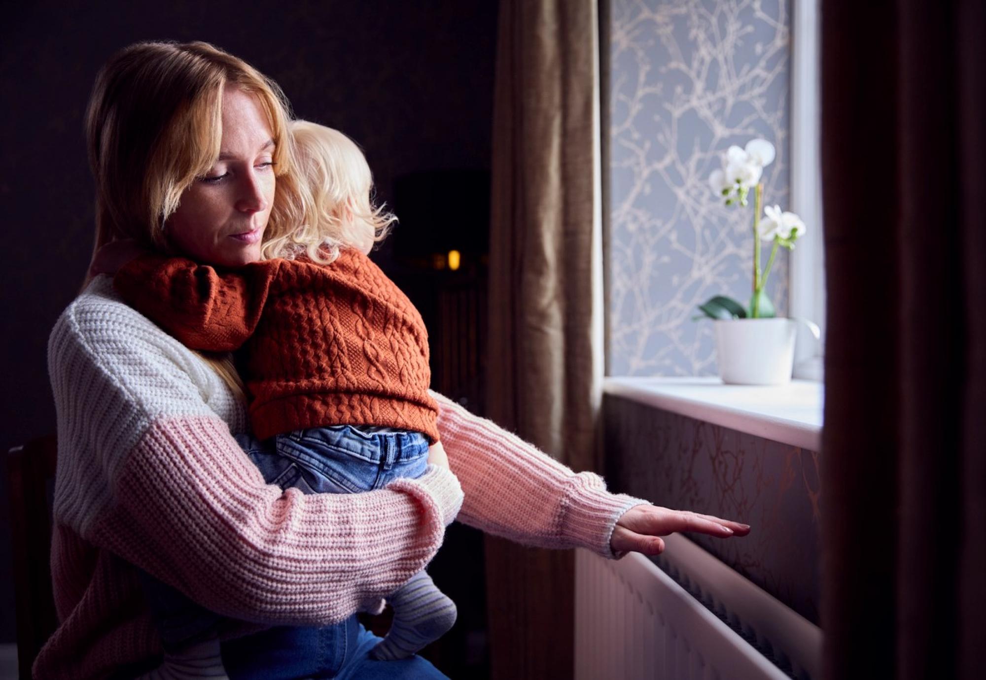 Woman looking out of a window with a child in her arms