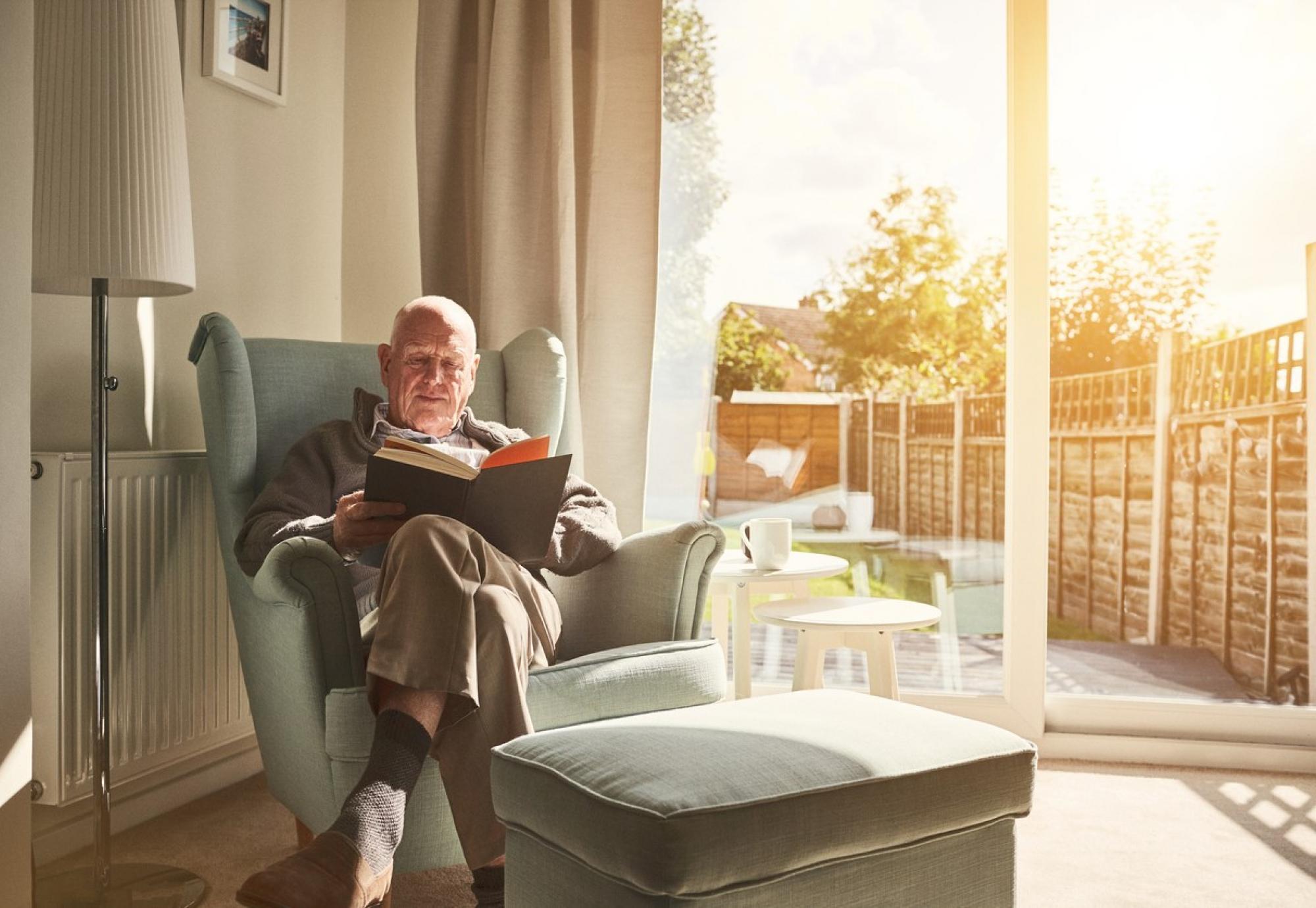 Old man reading in his home