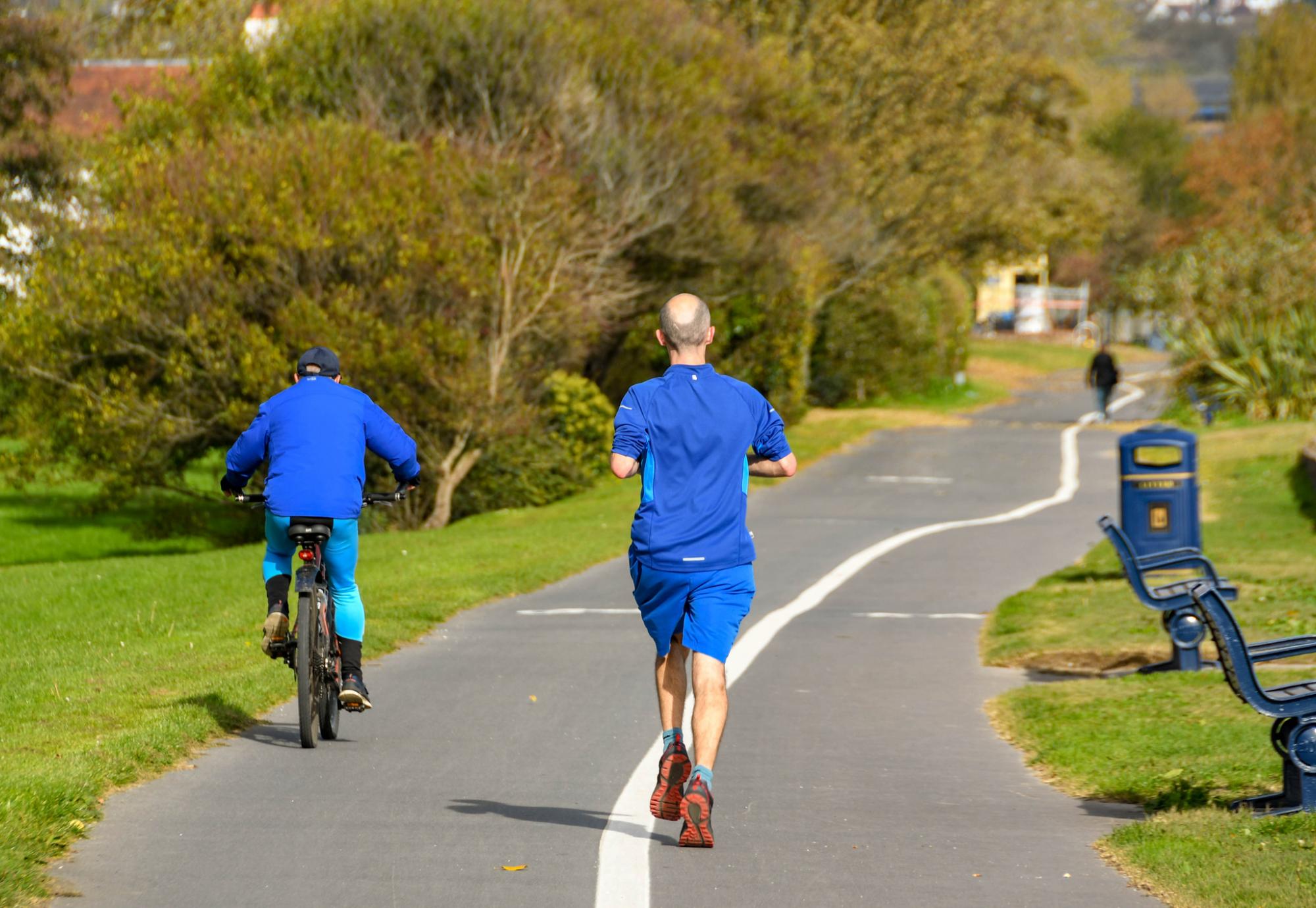 Person jogging behind a cyclist on the Wales National Coastal Path