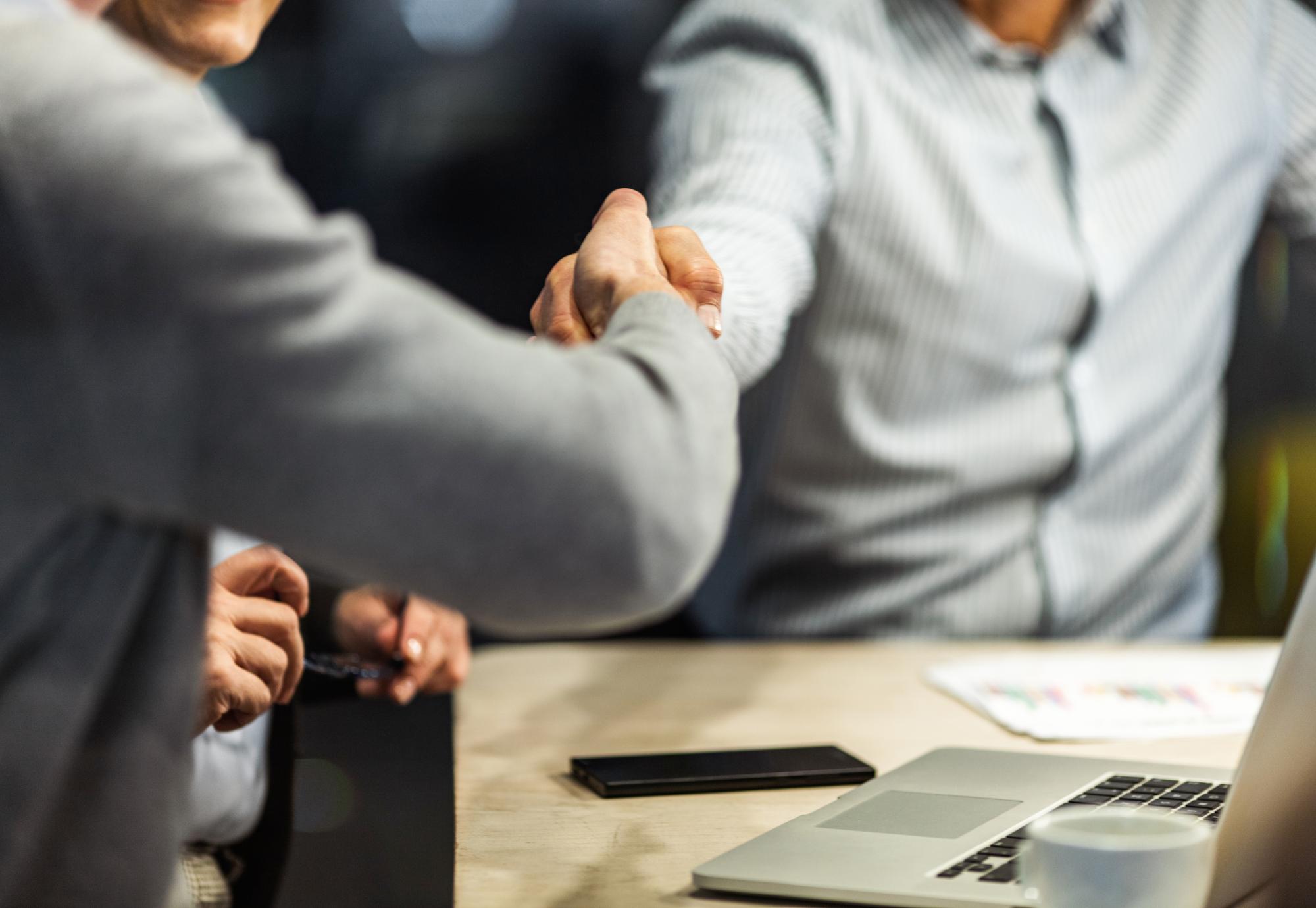 Two people shaking hands over a business agreement