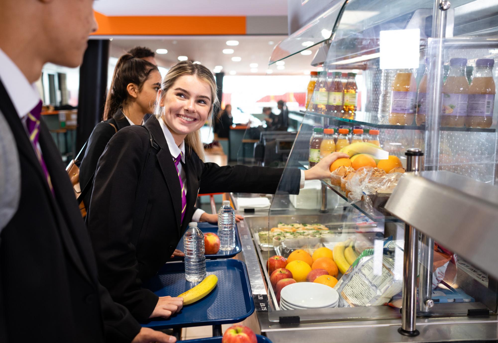 Schoolgirl smiling in the queue for lunch at school