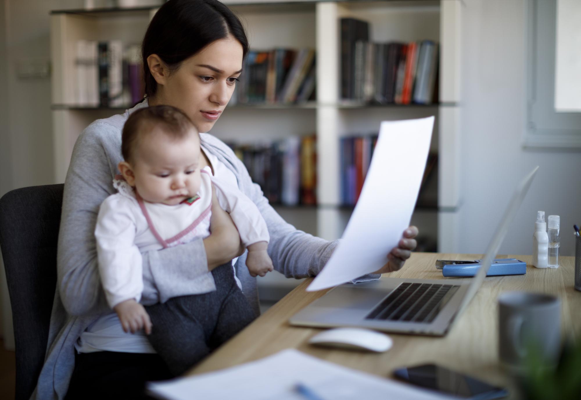 Woman holding baby and looking at a bill