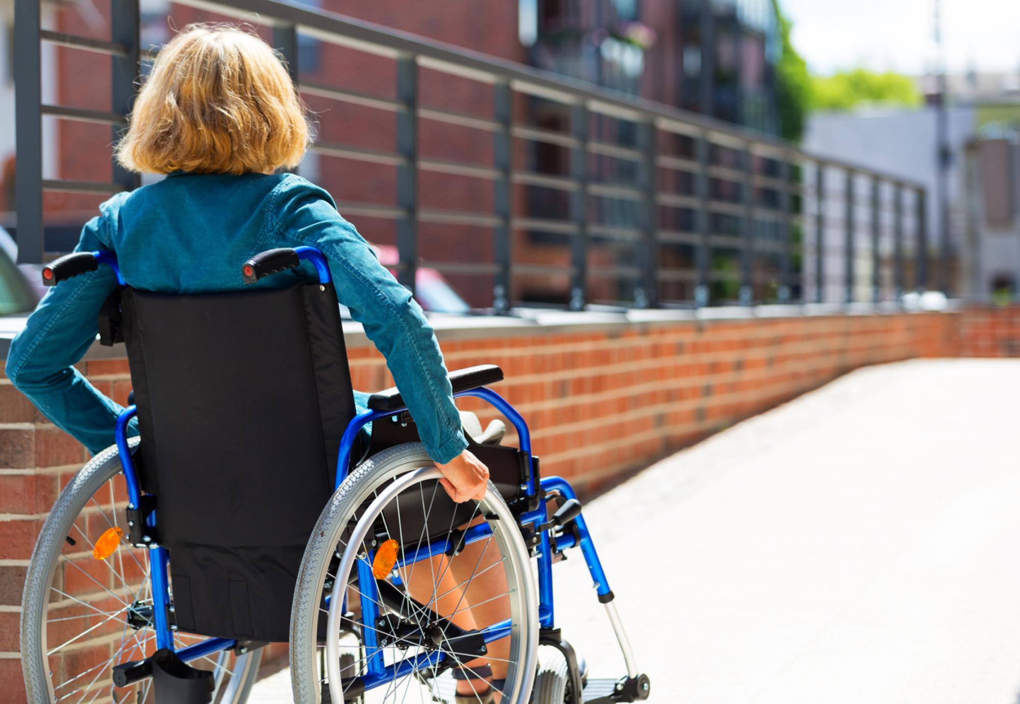 Woman sat in a wheelchair, going up a ramp