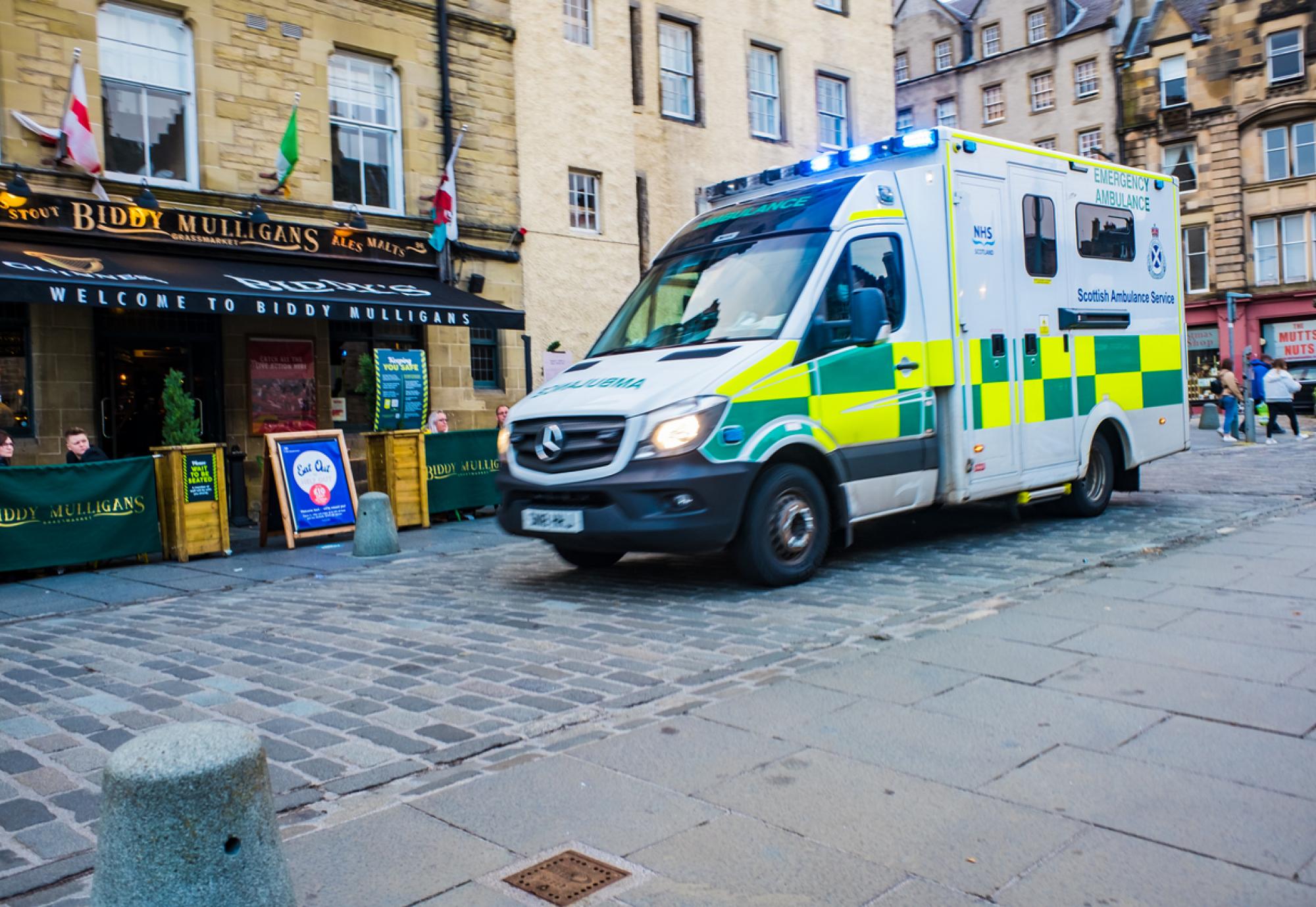 Emergency Ambulance driving through Grassmarket in Edinburgh