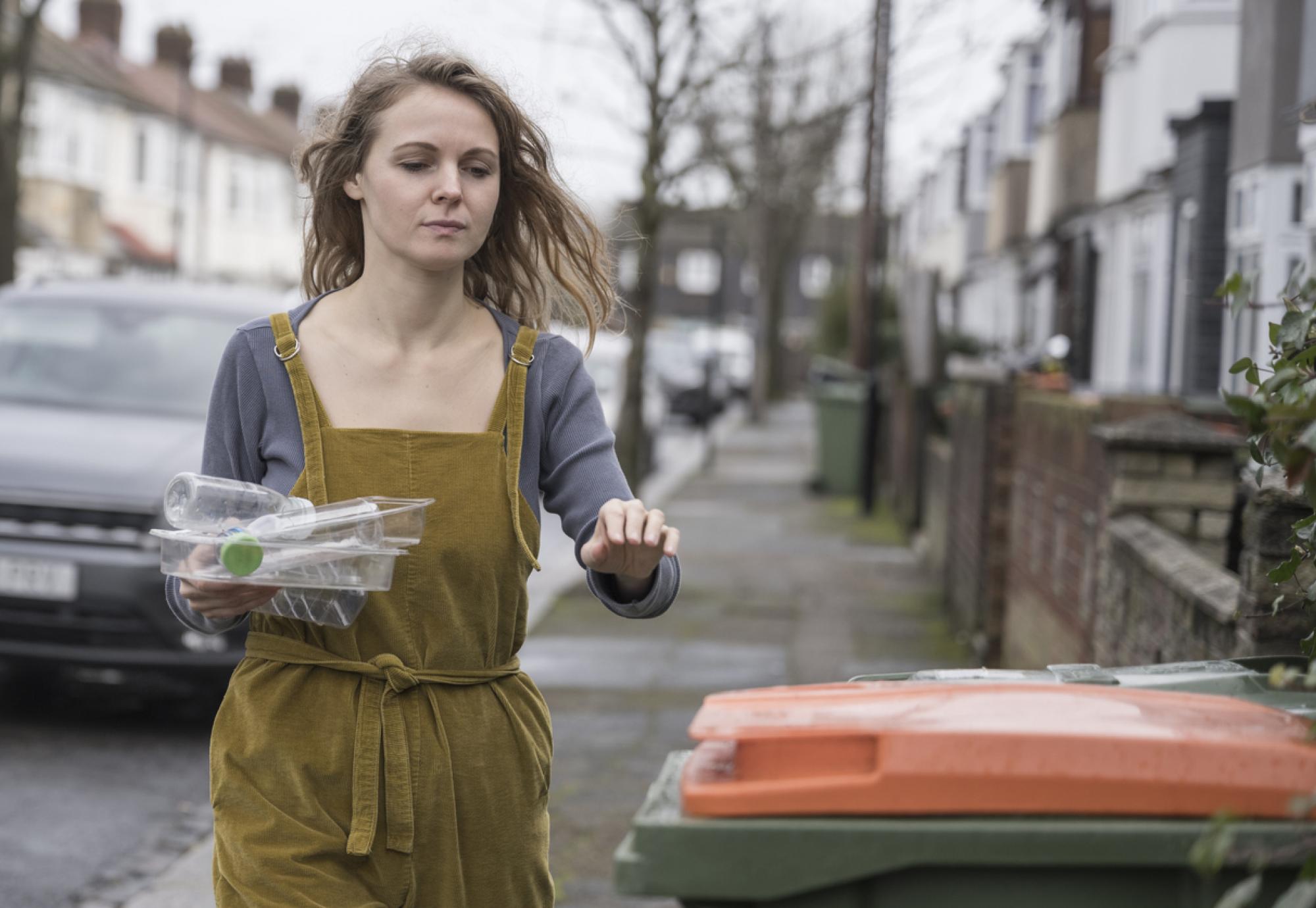 Mid adult British woman recycling plastic containers