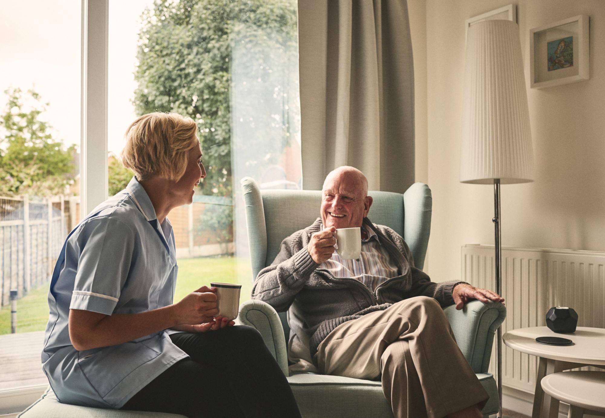 Relaxed senior man and female nurse having coffee