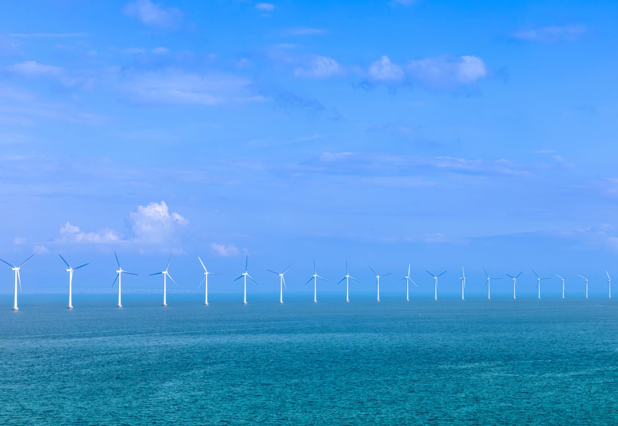 Renewable energy wind power plant and wind turbines along sea shoreline