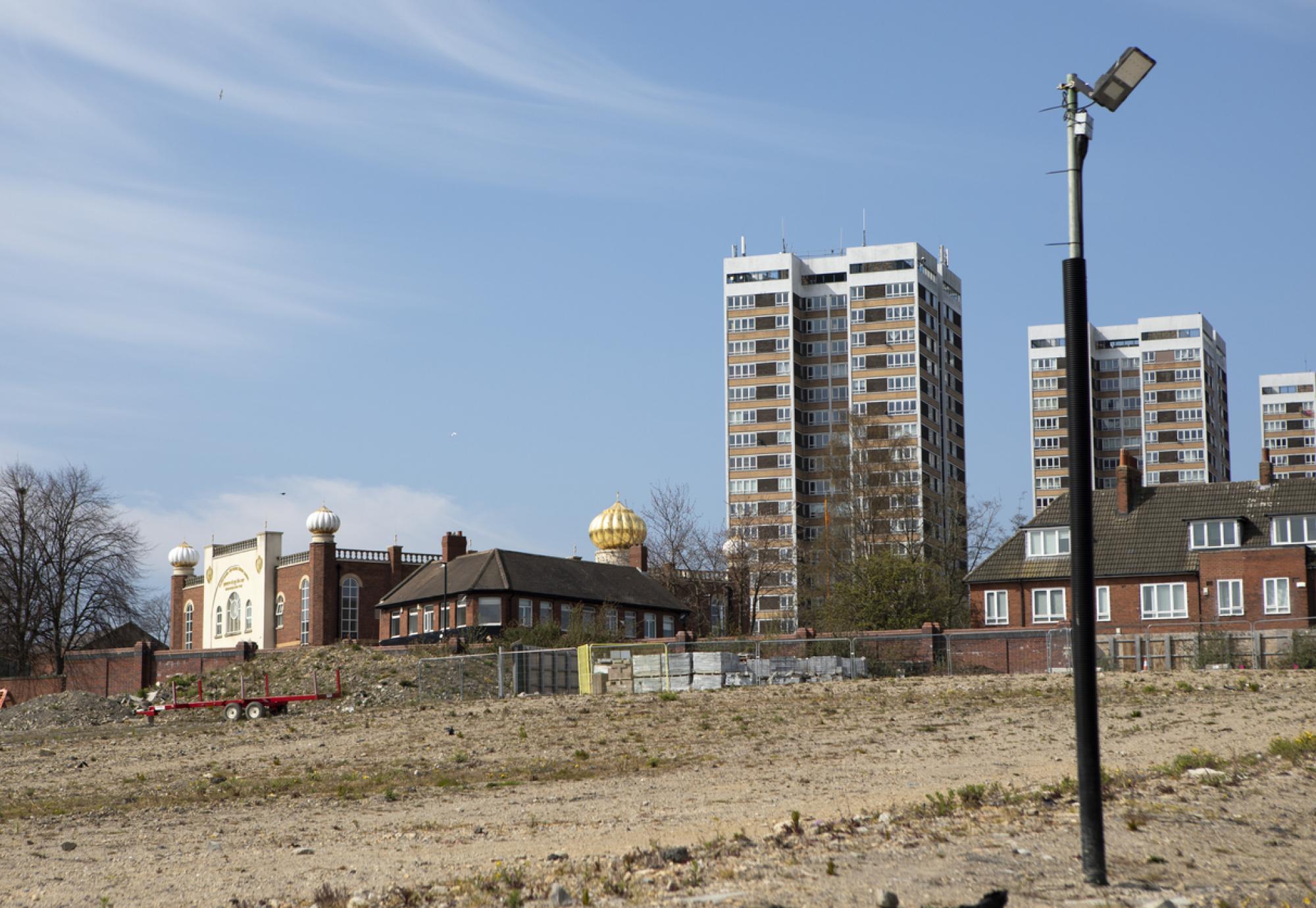 housing against a clear sky with barren land ready for development in the foregound