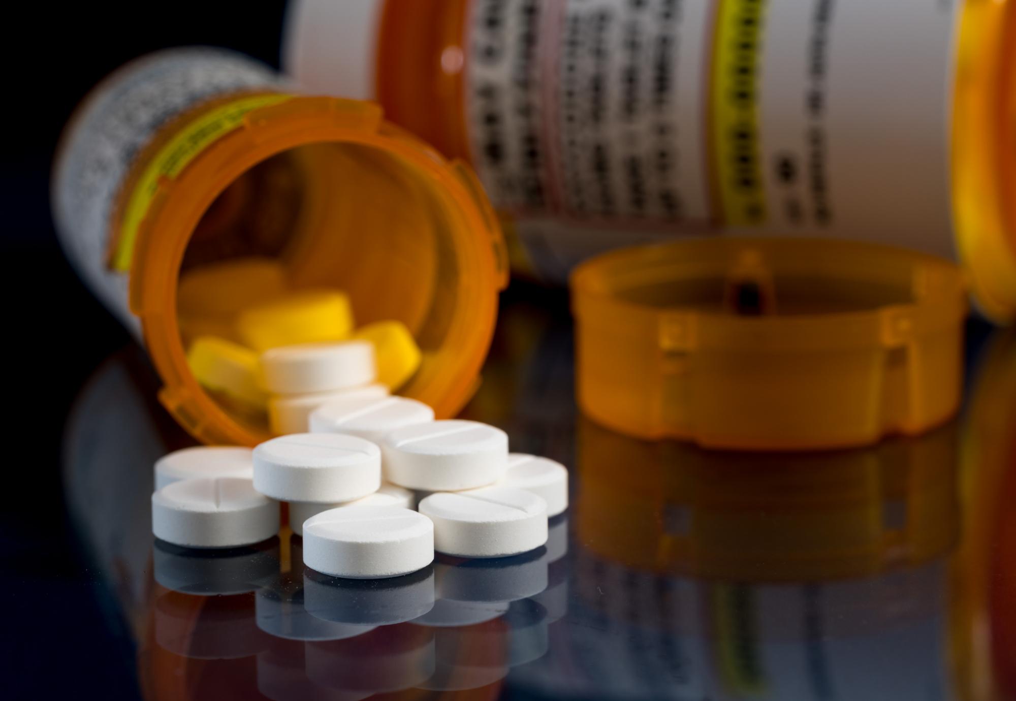 Prescription bottle for Oxycodone tablets and pills on glass table with reflections