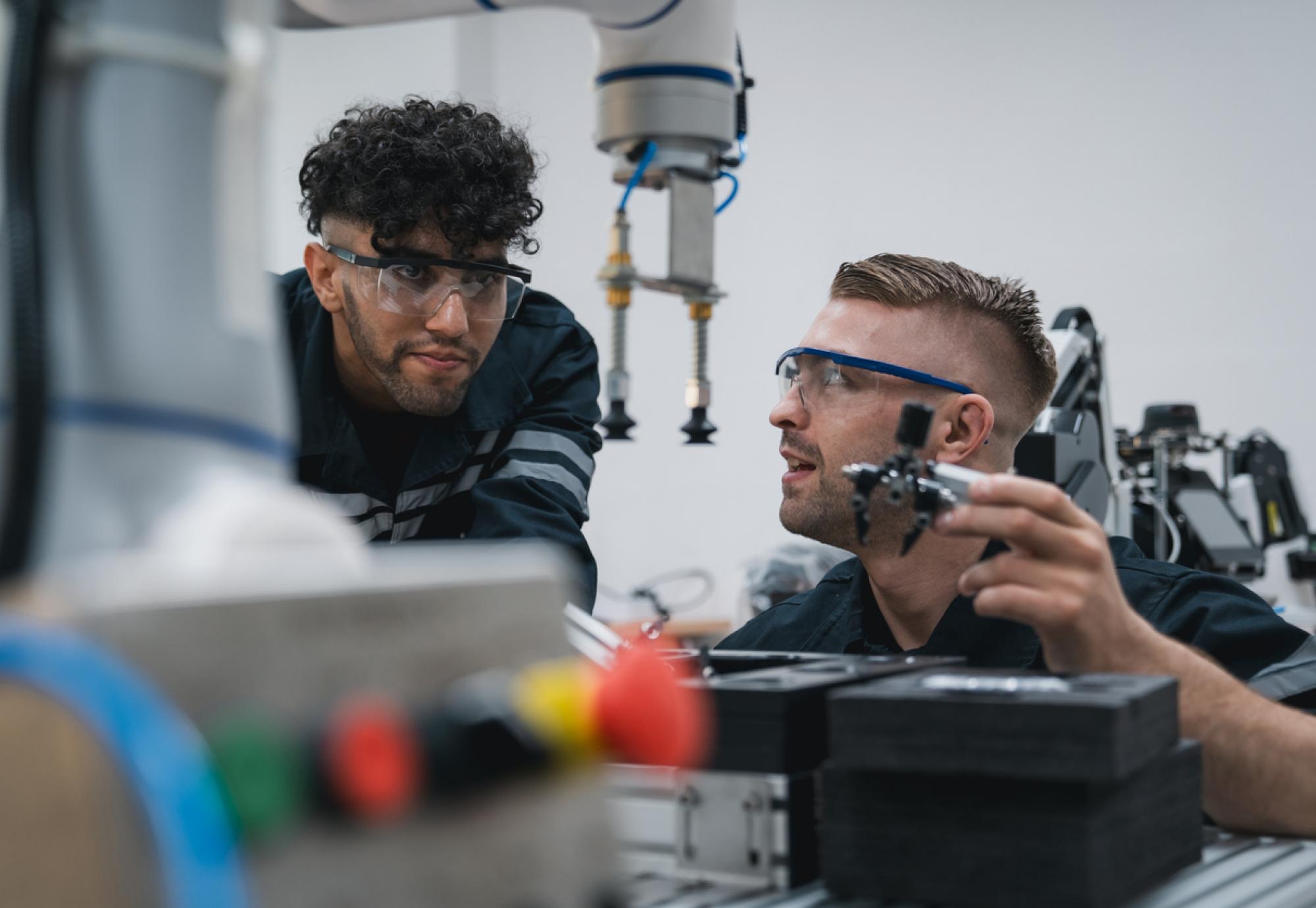 Student engineer Assembling Robotic Arm with computer in Technology Workshop